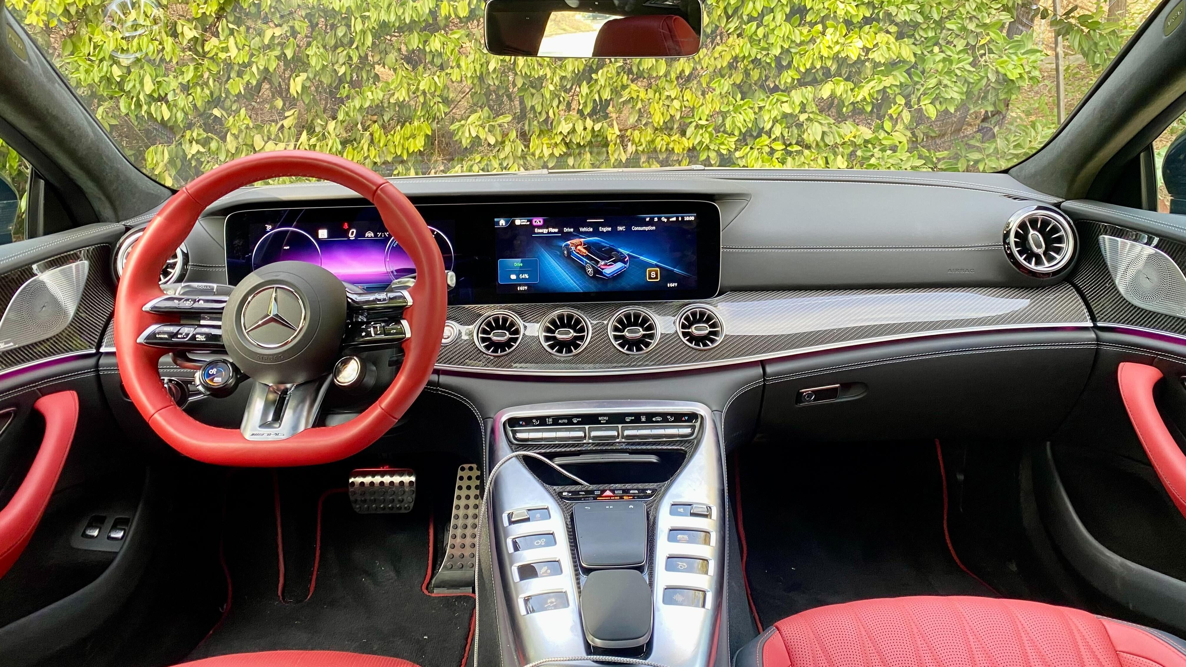 A photo showing the driver's pov and the dashboard with the red-rimmed steering wheel