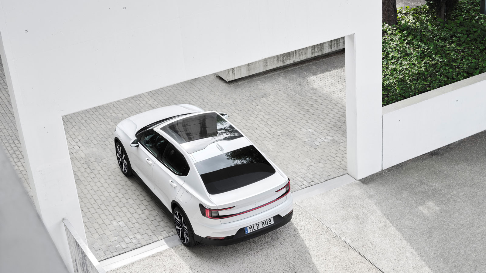 A photo of a white Polestar 2 EV on a driveway. 