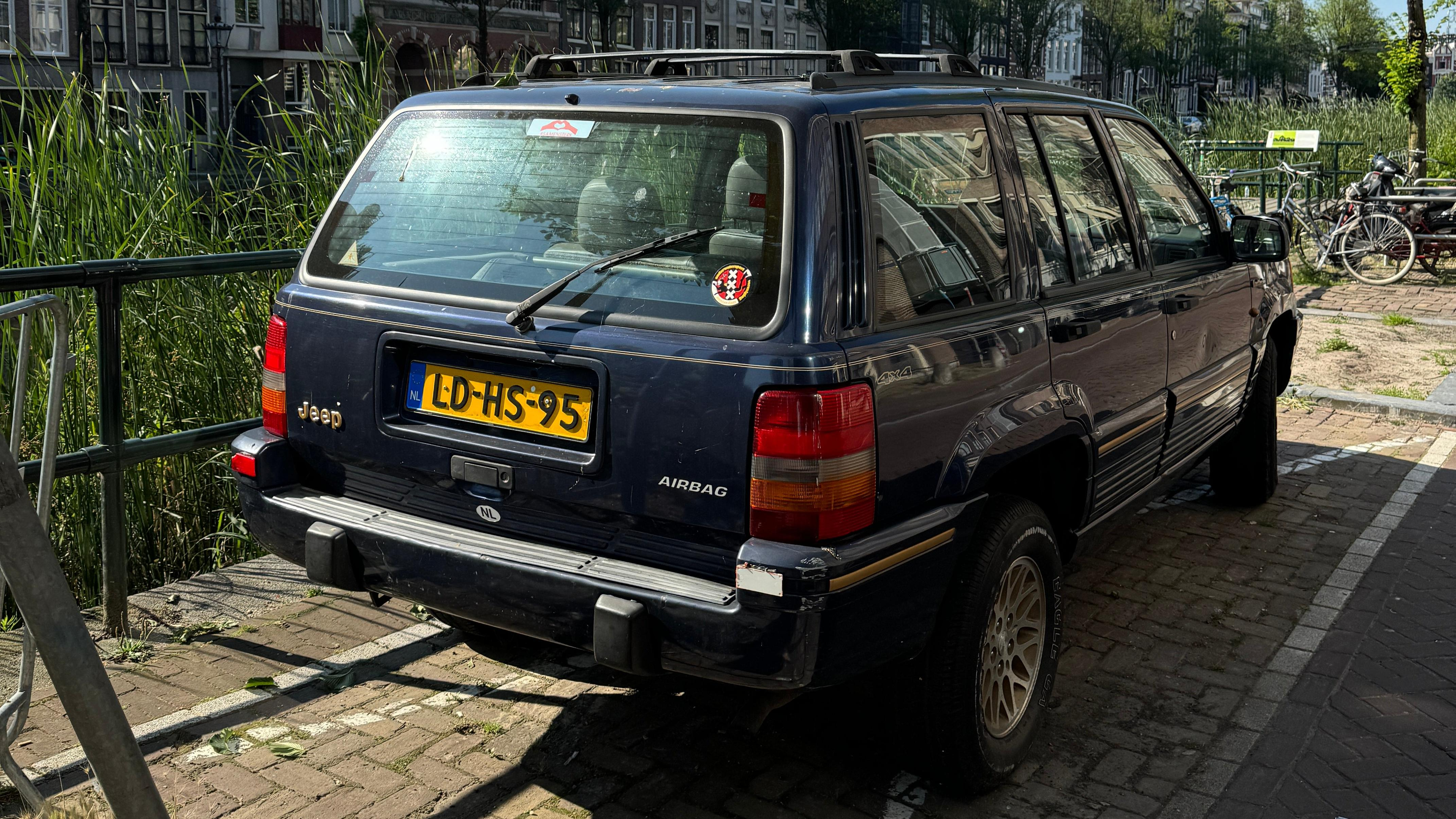 Rear 3/4 view of an old blue Jeep Grand Cherokee