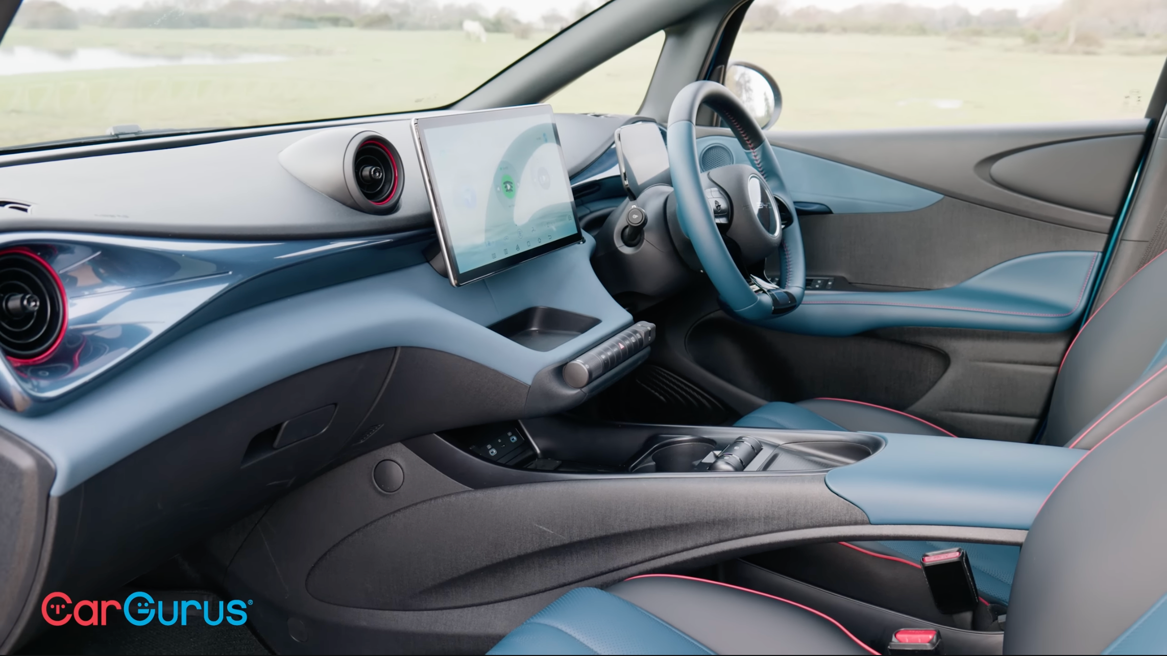 A view into the passenger door of a BYD Dolphin with the same teal and black color scheme taken from a CarGurus review on YouTube.