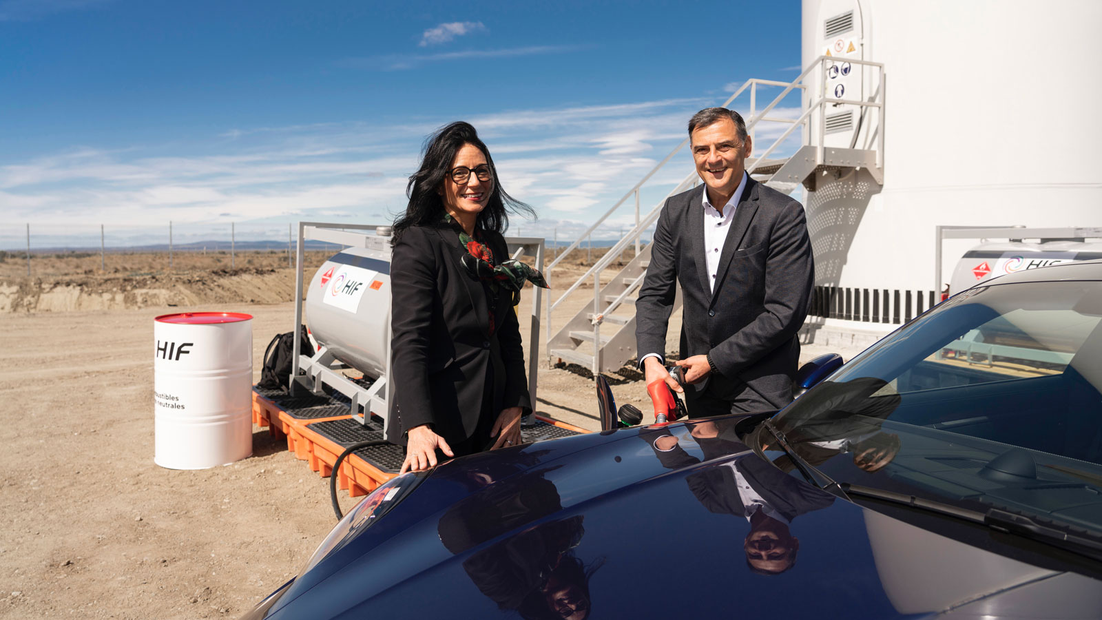 A photo of Michael Steiner and Barbara Frenkel filling a Porsche 911 with gas. 