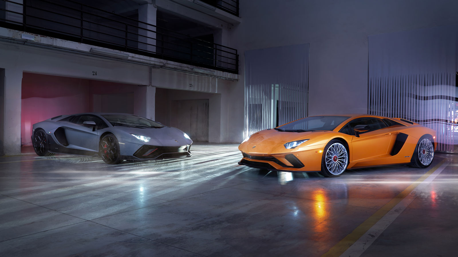 A photo of two Lamborghini Aventadors in a studio. 