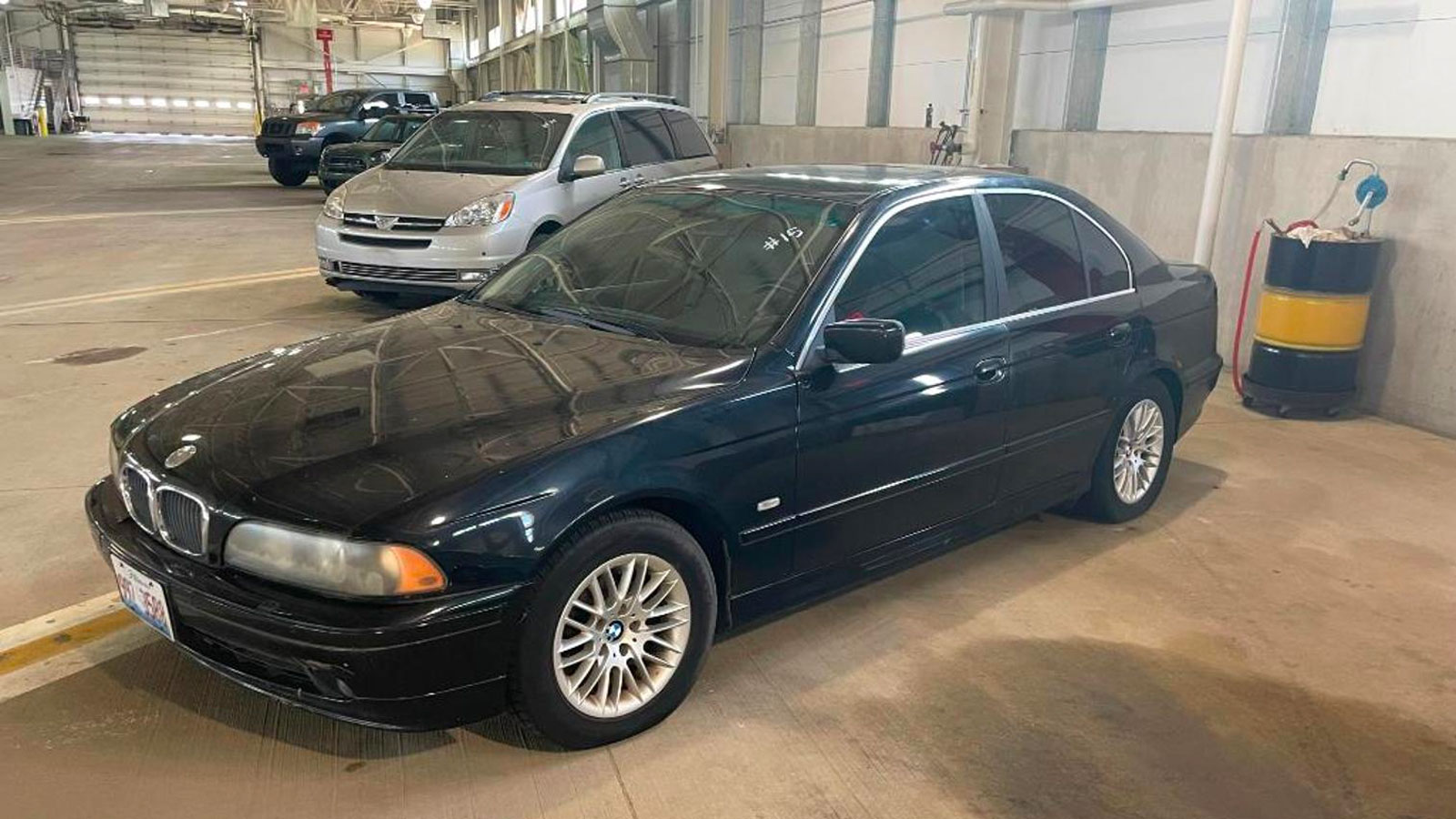 A black BMW 530i with blacked out windows in a warehouse 