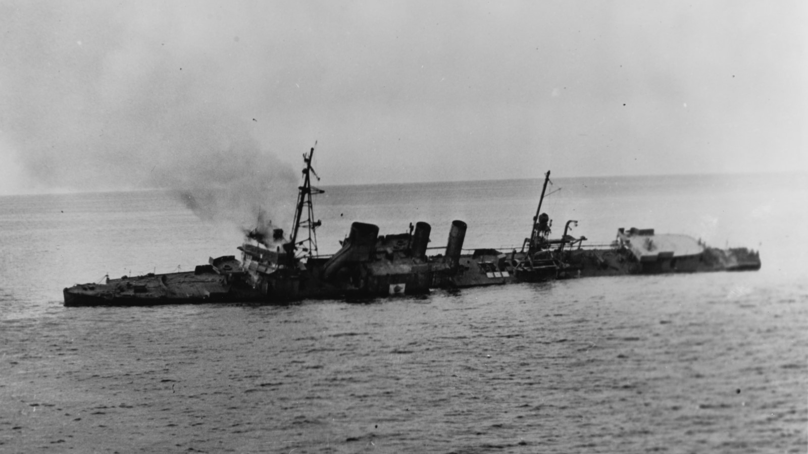 A photo of a ship listing to one side after being shot. 