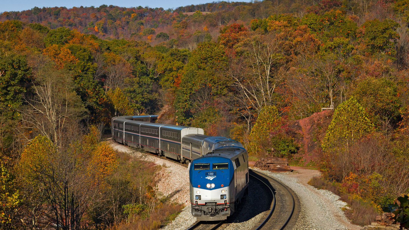 An Amtrak train passes through a forrest in Fall