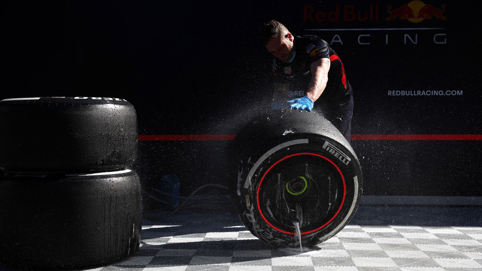 A Red Bull F1 mechanic cleans down a set of wheels. 