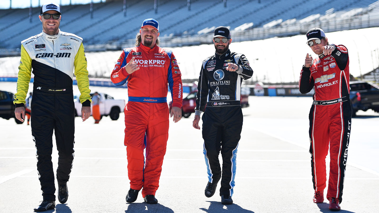 Four NASCAR drivers walk along the track