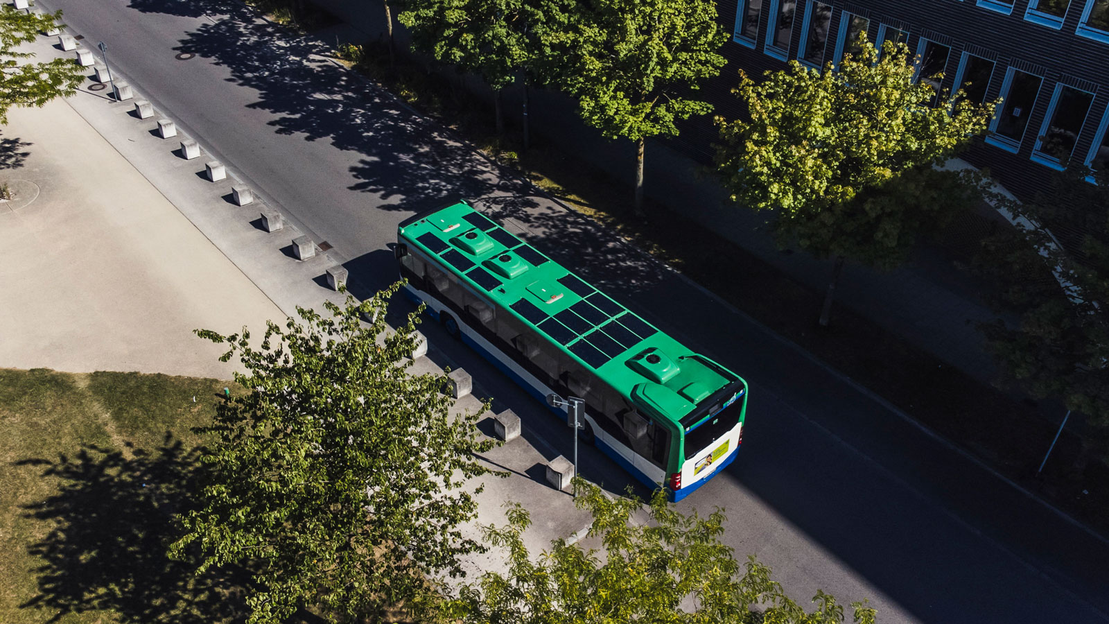 A photo showing a green bus with solar panels covering its roof. 