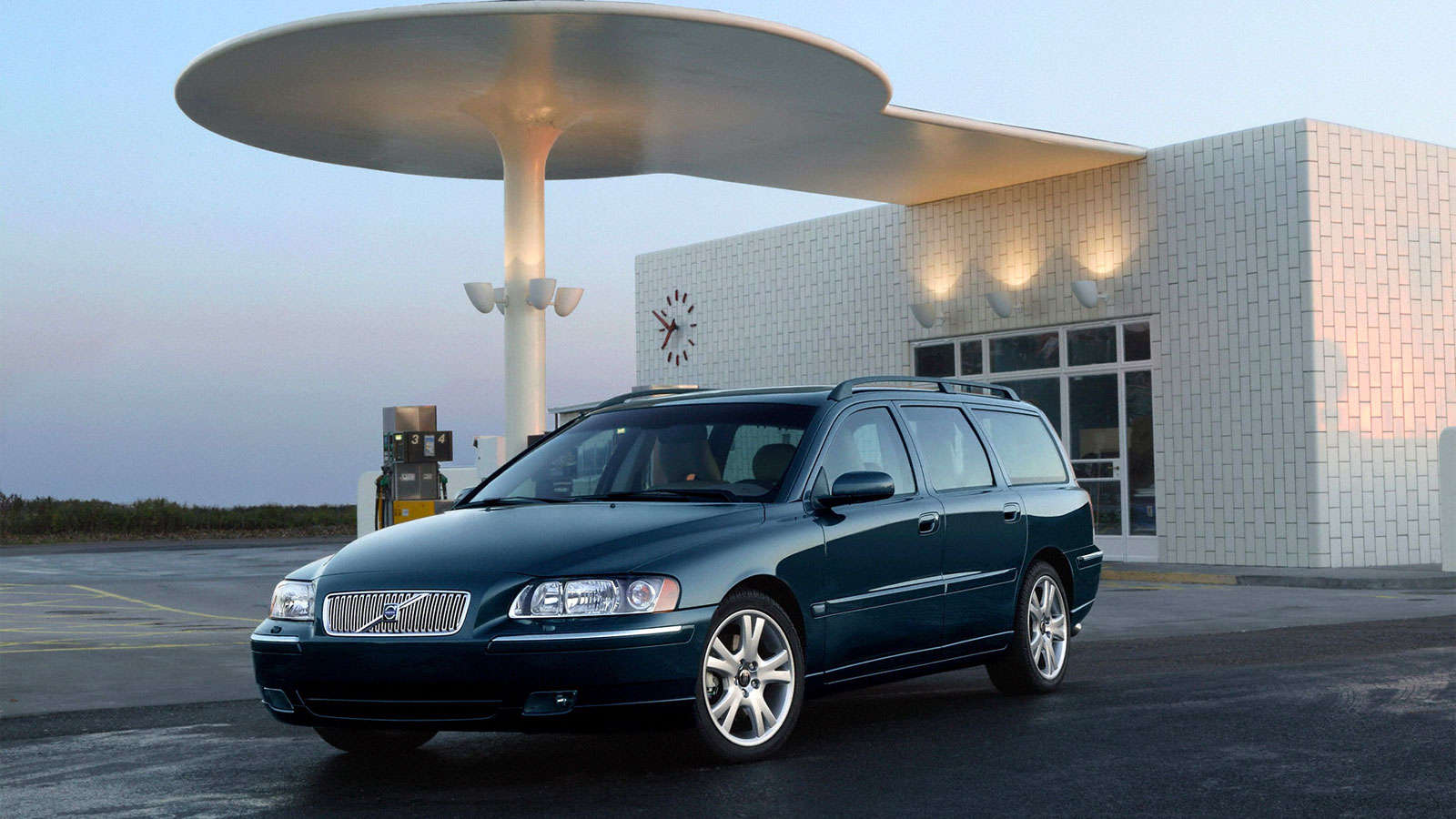 A photo of a blue Volvo V70 parked outside a house. 