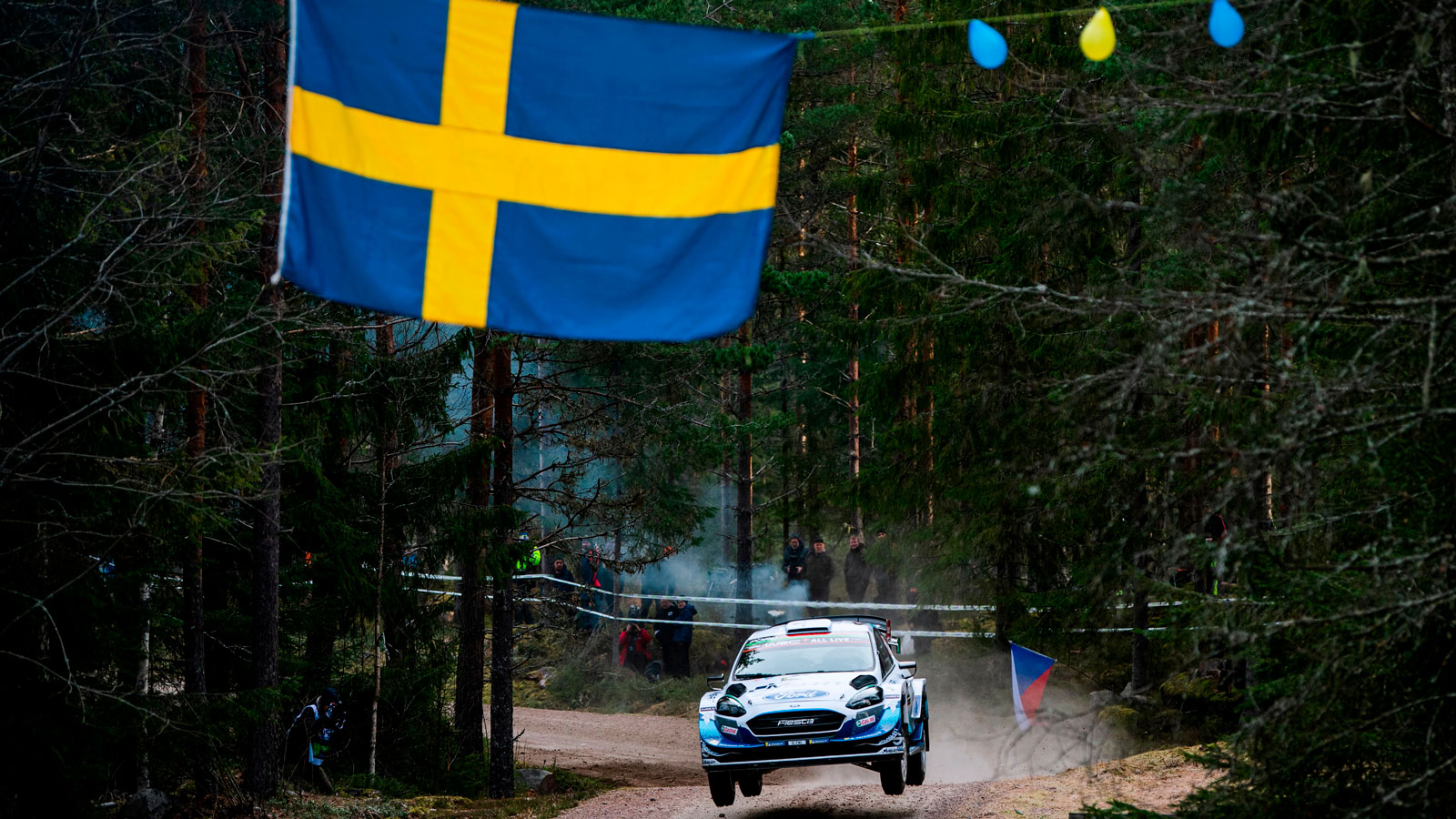 A rally car jumps a mound in Rally Sweden. 