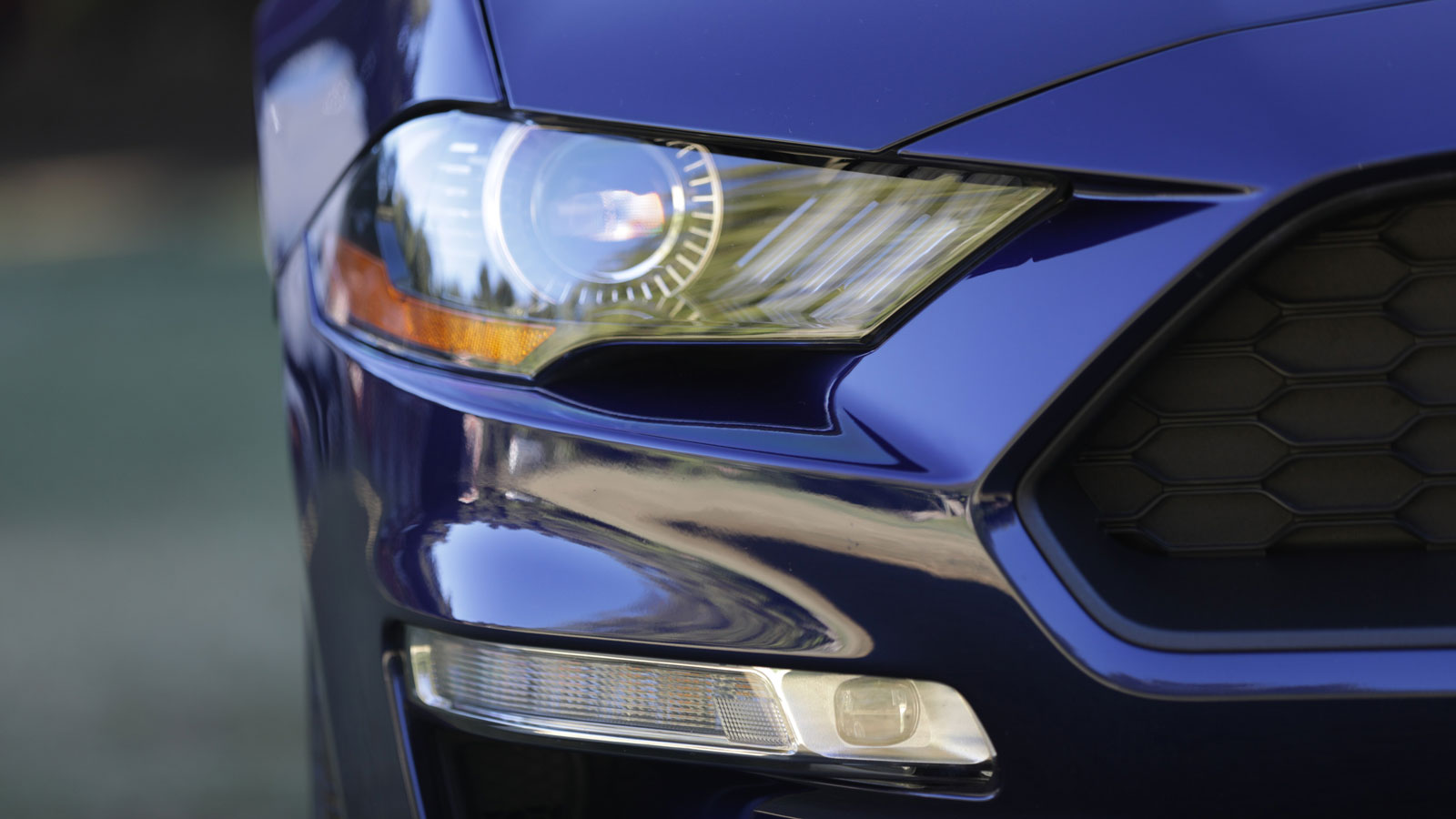 A close up photo of the headlamp on a 2020 Ford Mustang that is painted blue. 