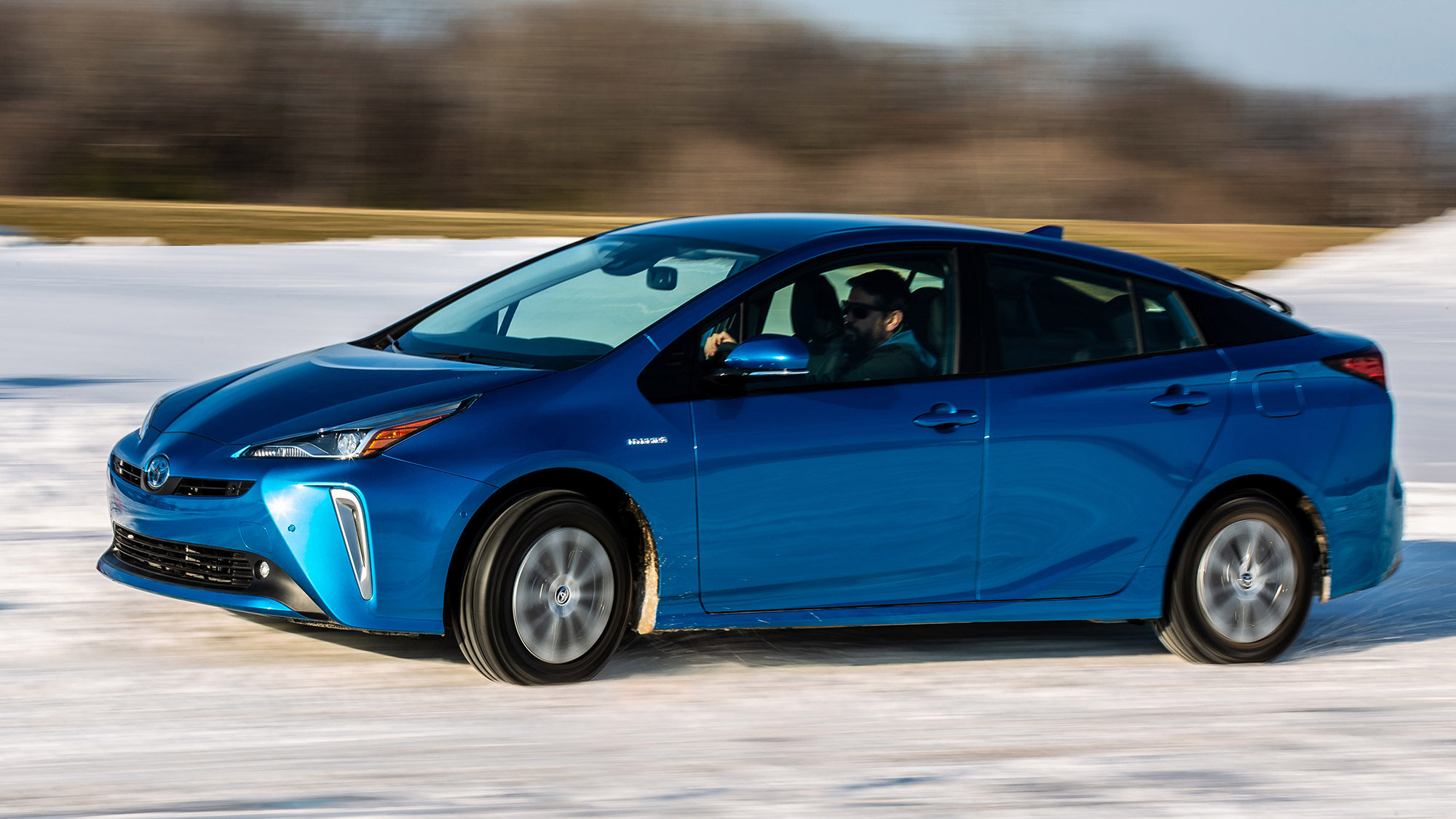 Blue Toyota Prius side profile view while driving on snow