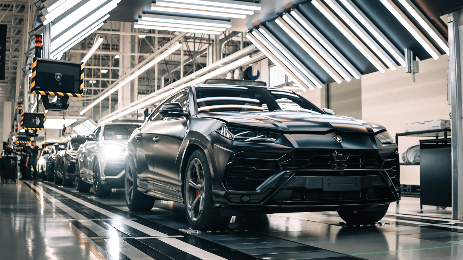 A Lamborghini Urus production line with five cars rolling along it. 