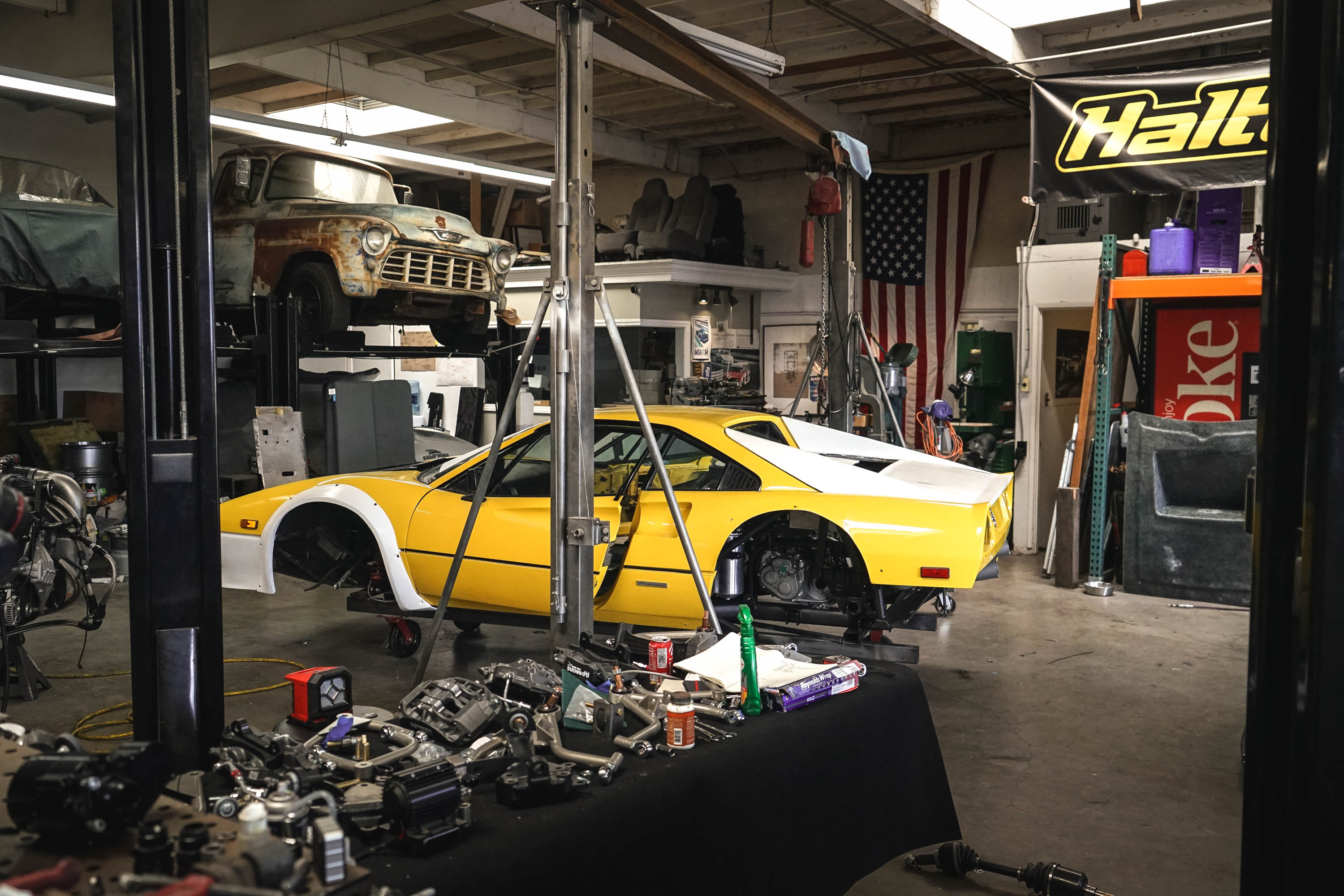 A highly modified yellow Ferrari in a messy shop.