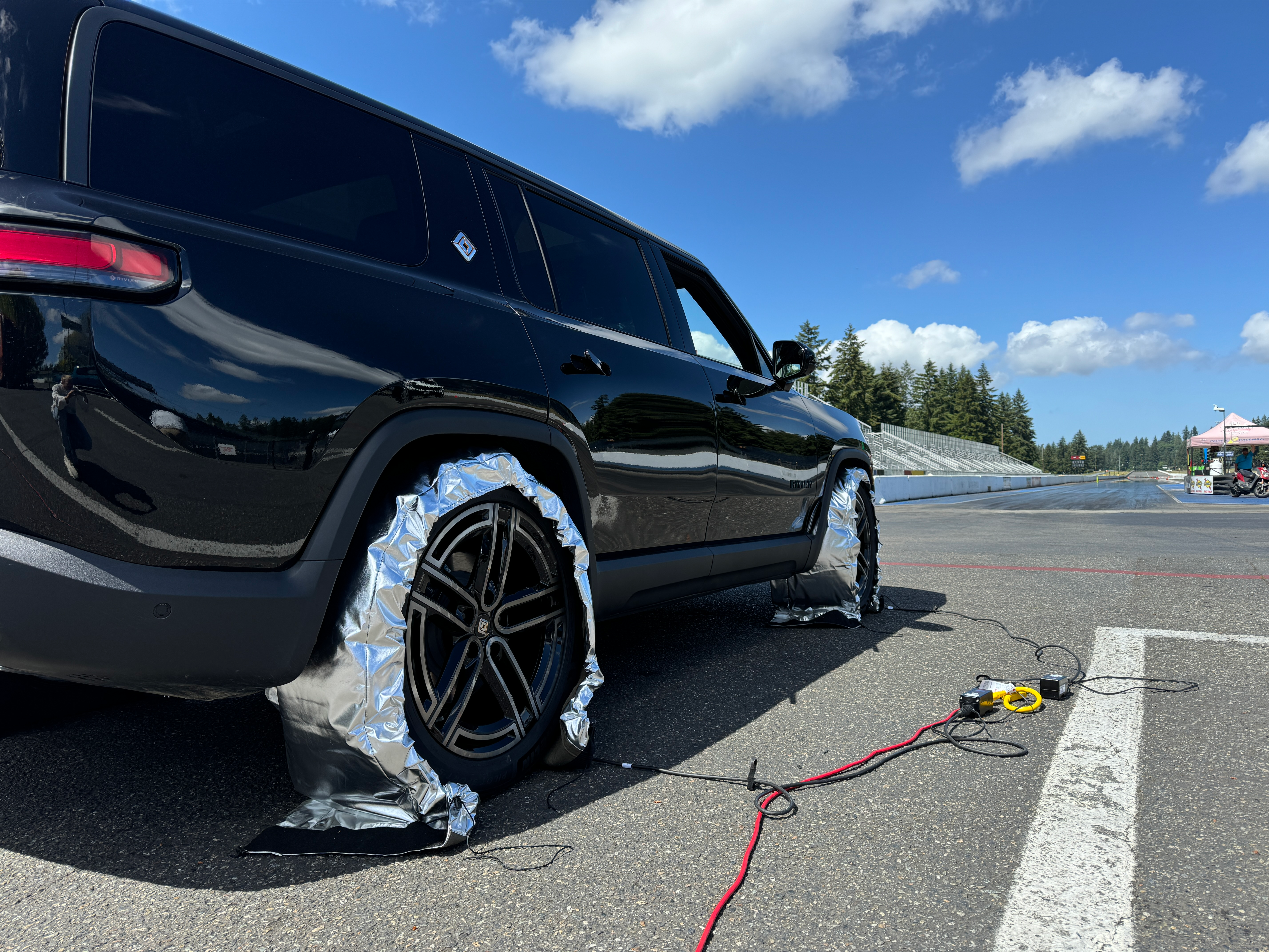 A black Rivian R1S getting prepped at a drag strip