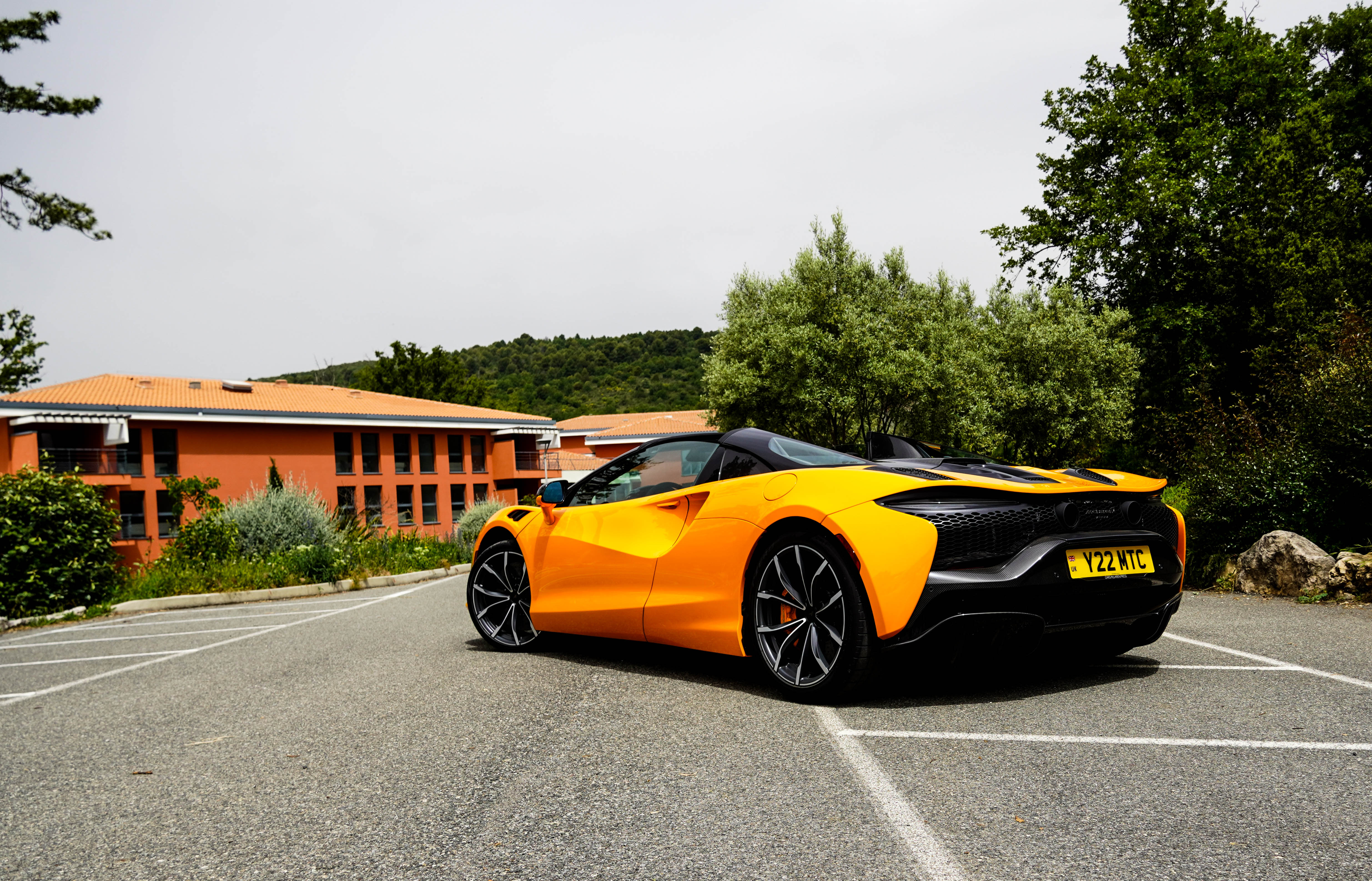 Rear 3/4 view of an orange McLaren Artura Spider