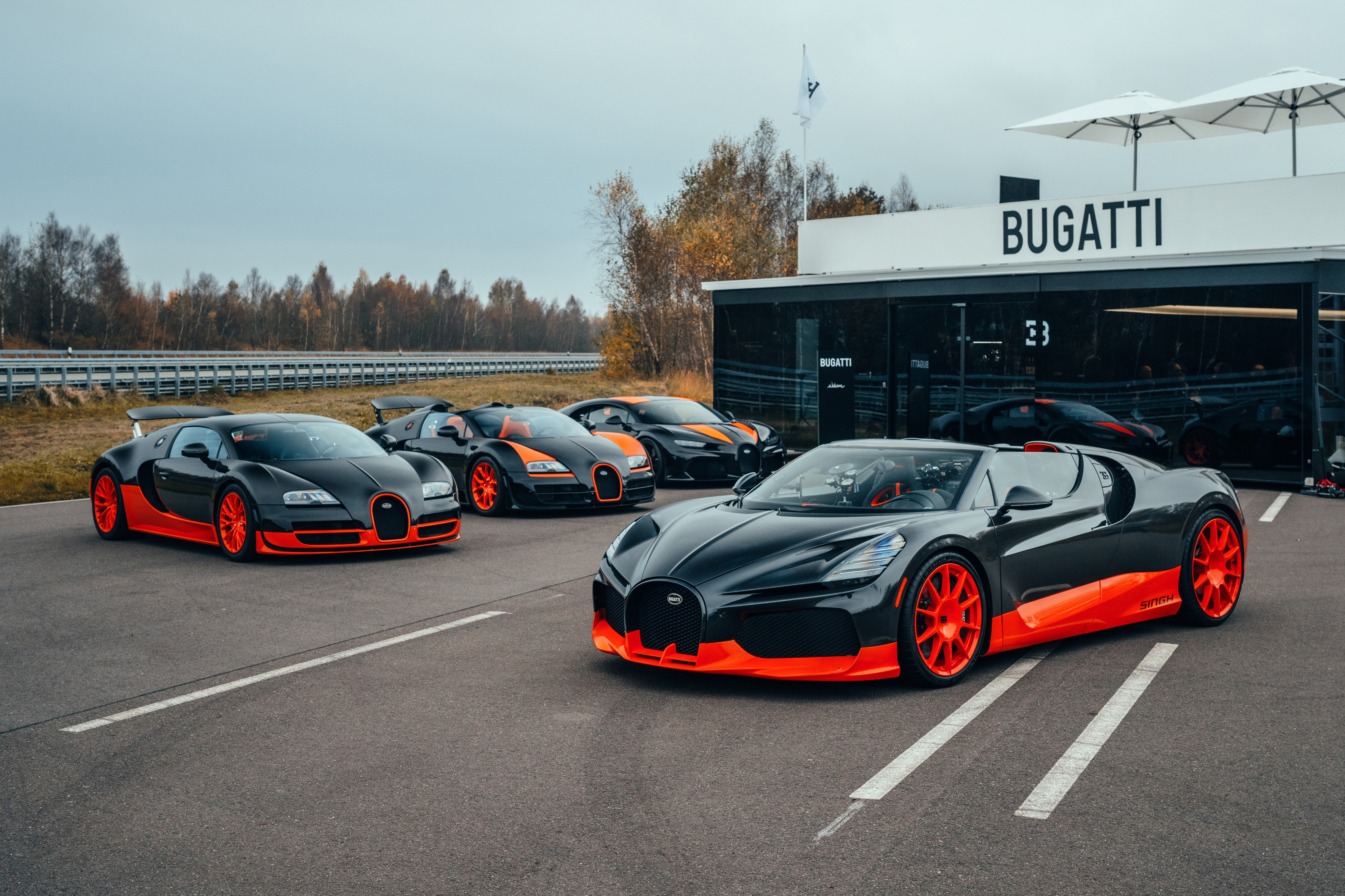 Black and orange Bugatti W16 Mistral World Record Car in front of other Bugatti World Record Editions