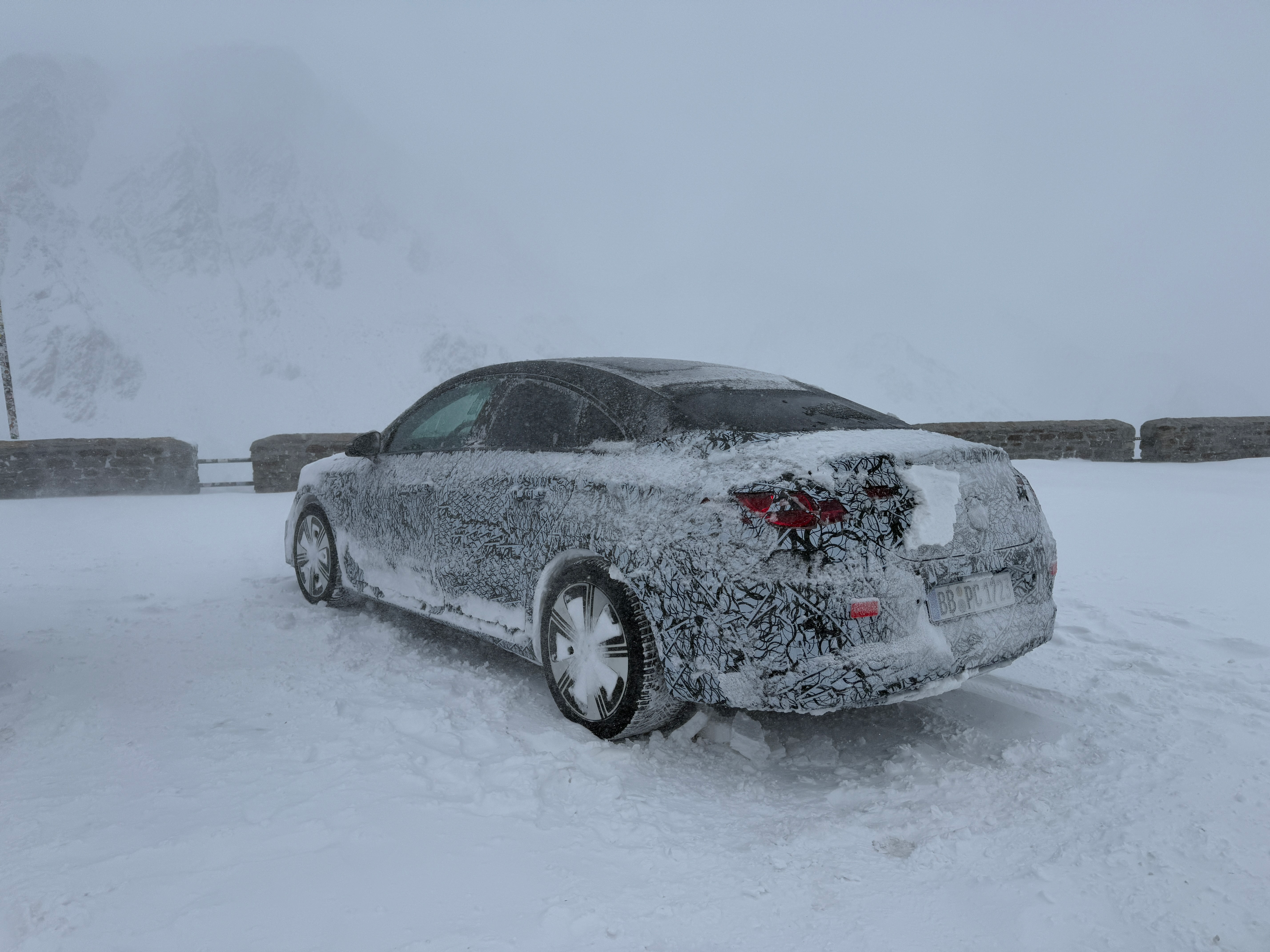 Rear 3/4 view of a camouflaged Mercedes-Benz CLA EV prototype