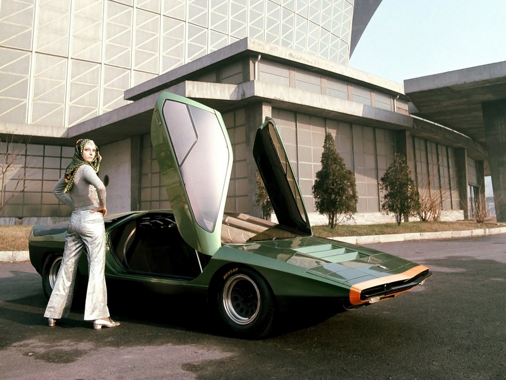 Front 3/4 view of the green Alfa Romeo 33 Carabo concept with the doors open and a woman posing in front