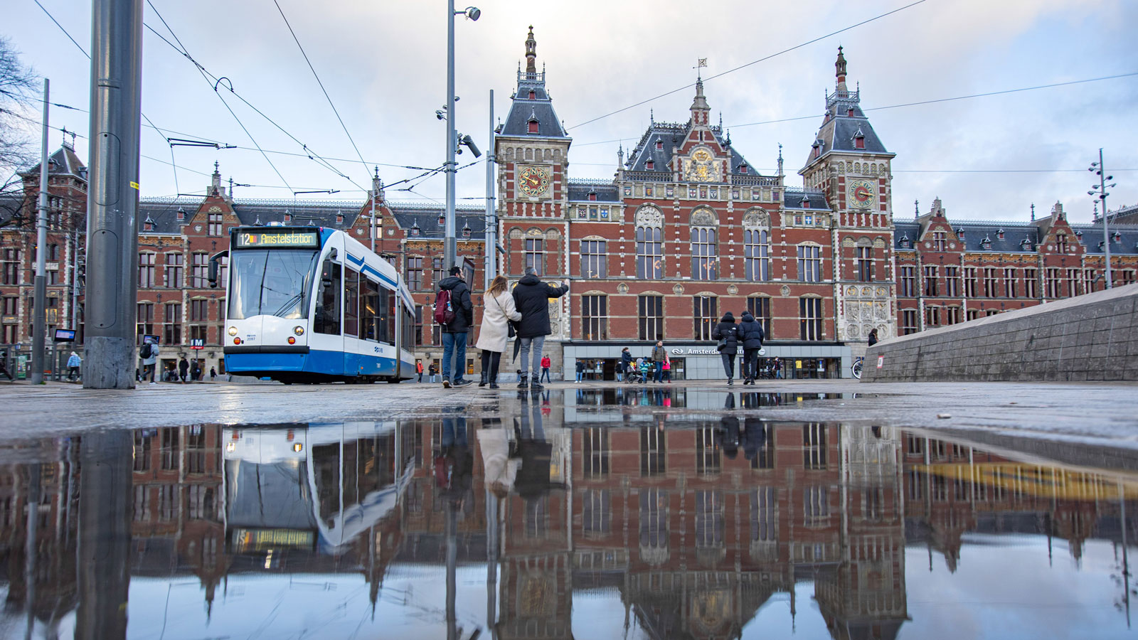 A photo of a tram passing the train station in Amsterdam. 