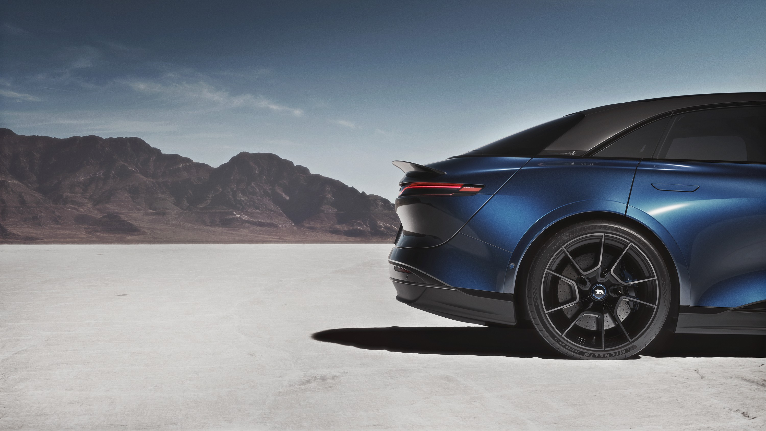 A blue EV sits on a salt flat, with its rear end in the frame of the photo.