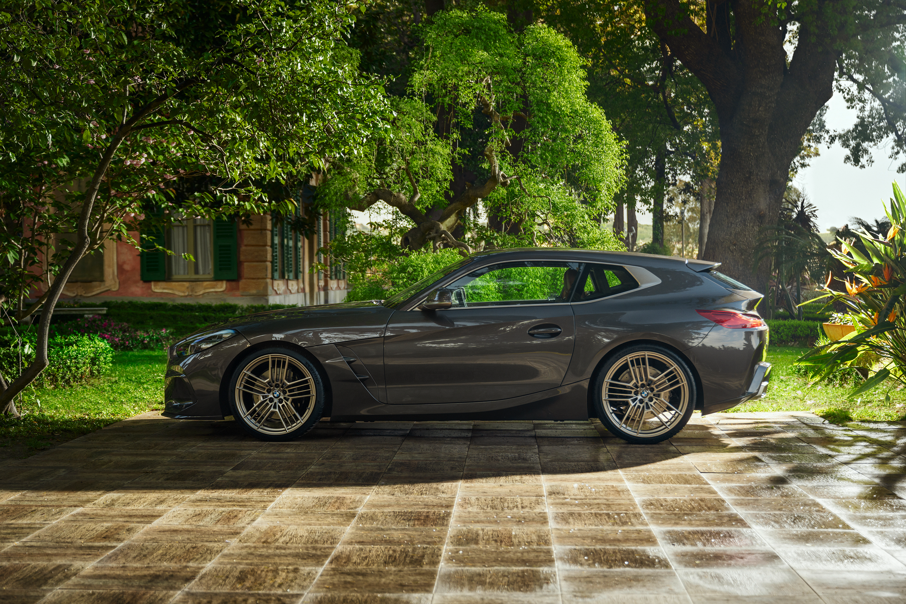 A BMW shooting brake concept car is parked on in front of a house and trees. Side view.