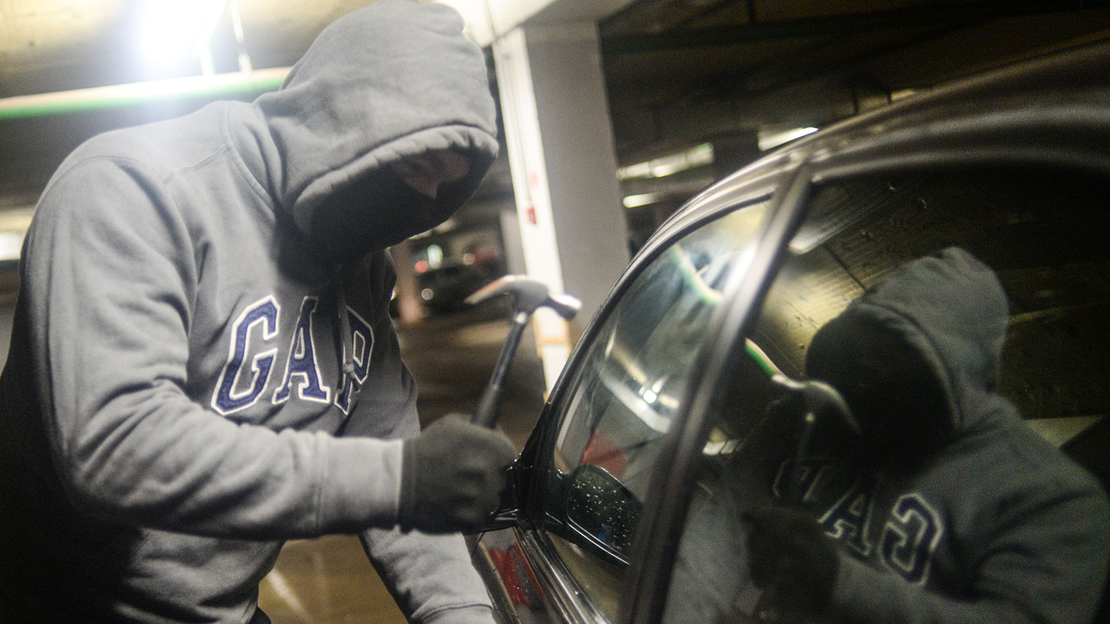 A photo of someone smashing a window on a car. 