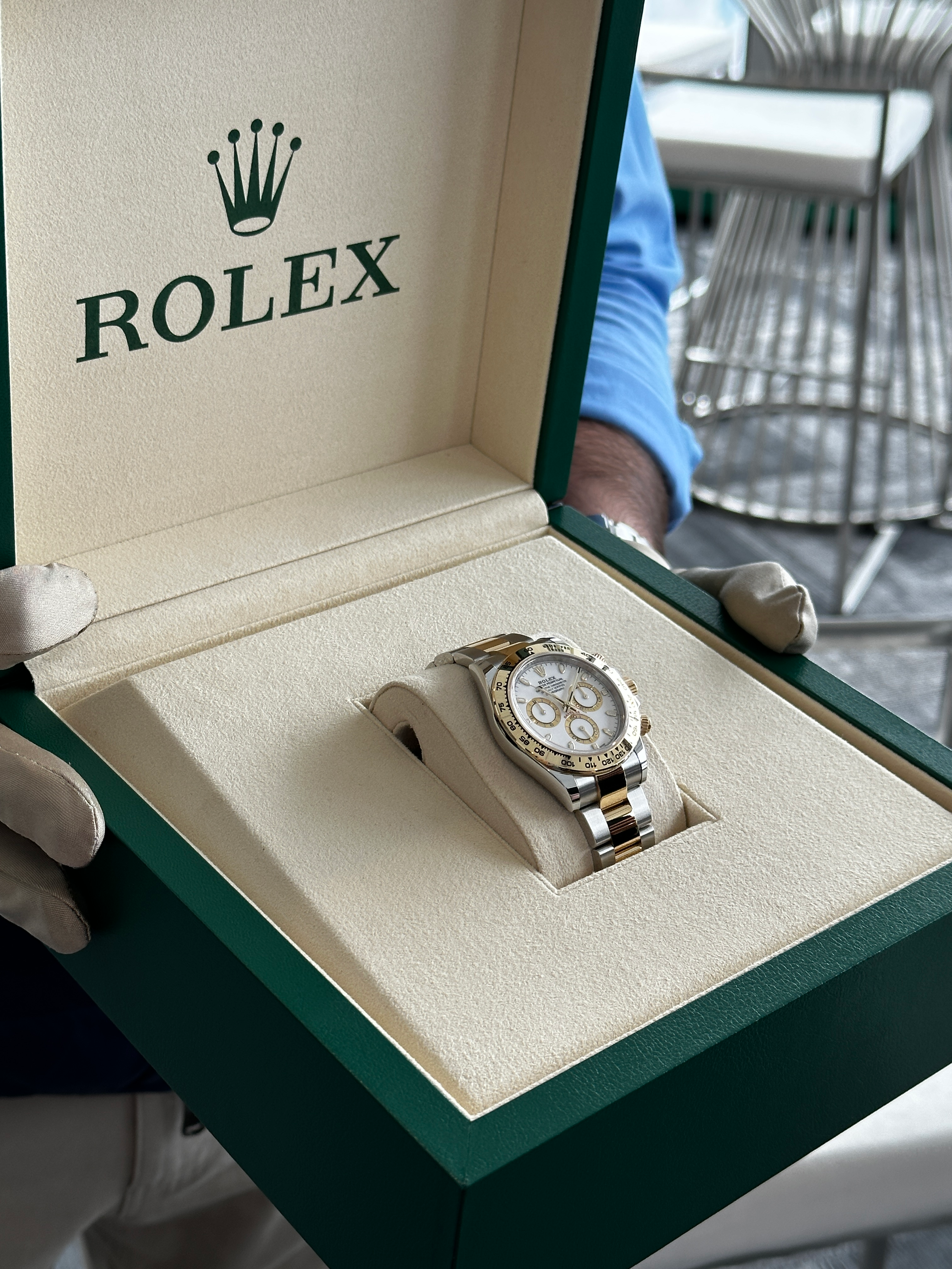 A two-tone Rolex Daytona in its green and tan presentation box.