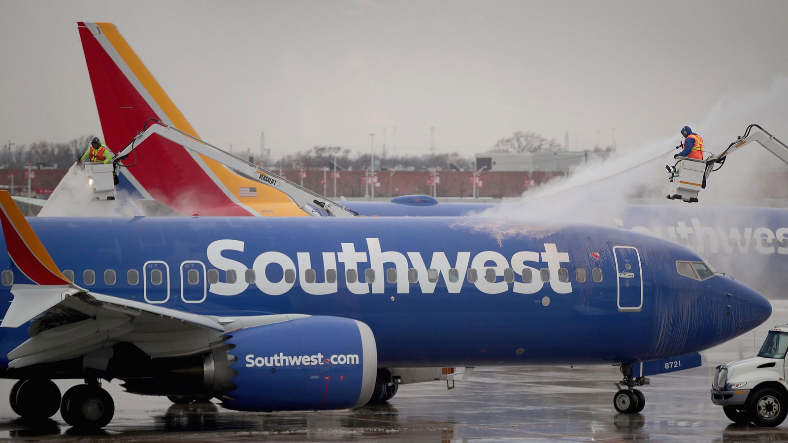 A photo of a Southwest plane being deiced at an airport. 