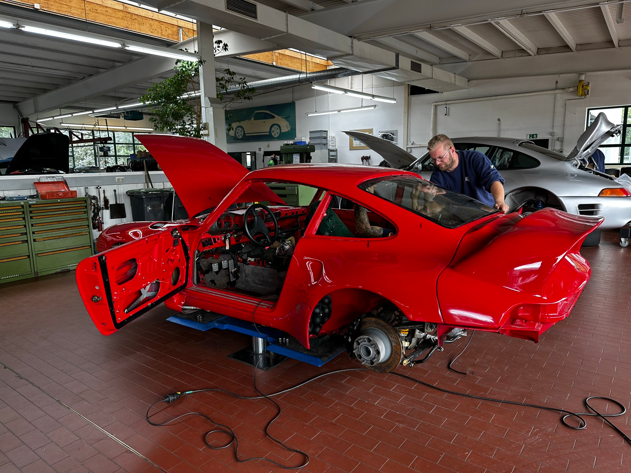 A Ruf technician works on restoring a customer's red classic turbo car