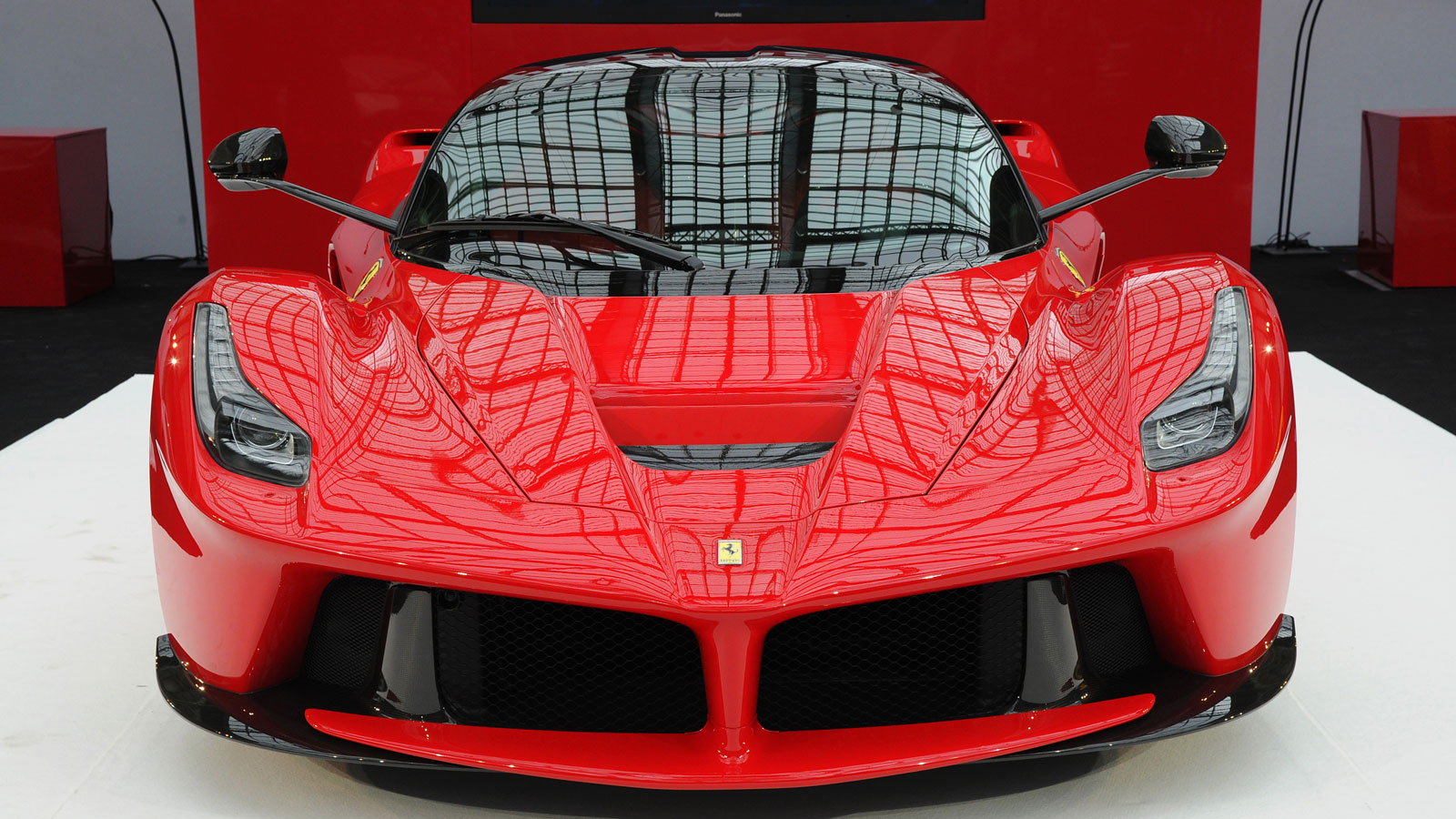 A photo of a bright red LaFerrari hypercar on a stand at a motorshow. 