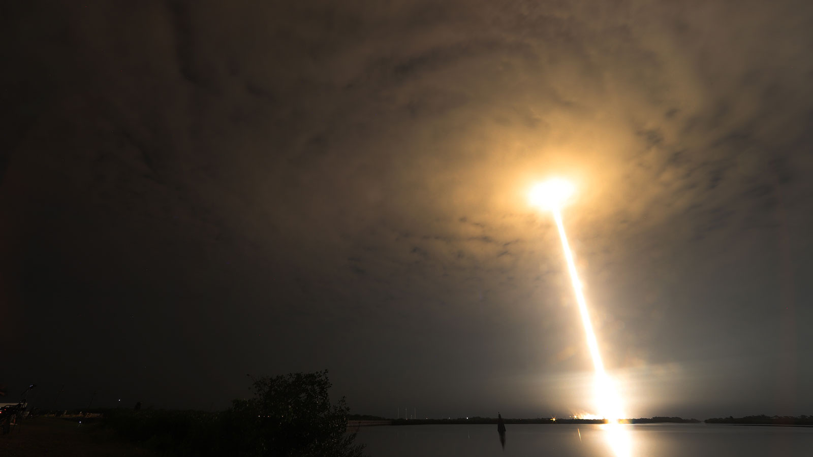 A photo of a SpaceX rocket launching through the clouds at night. 