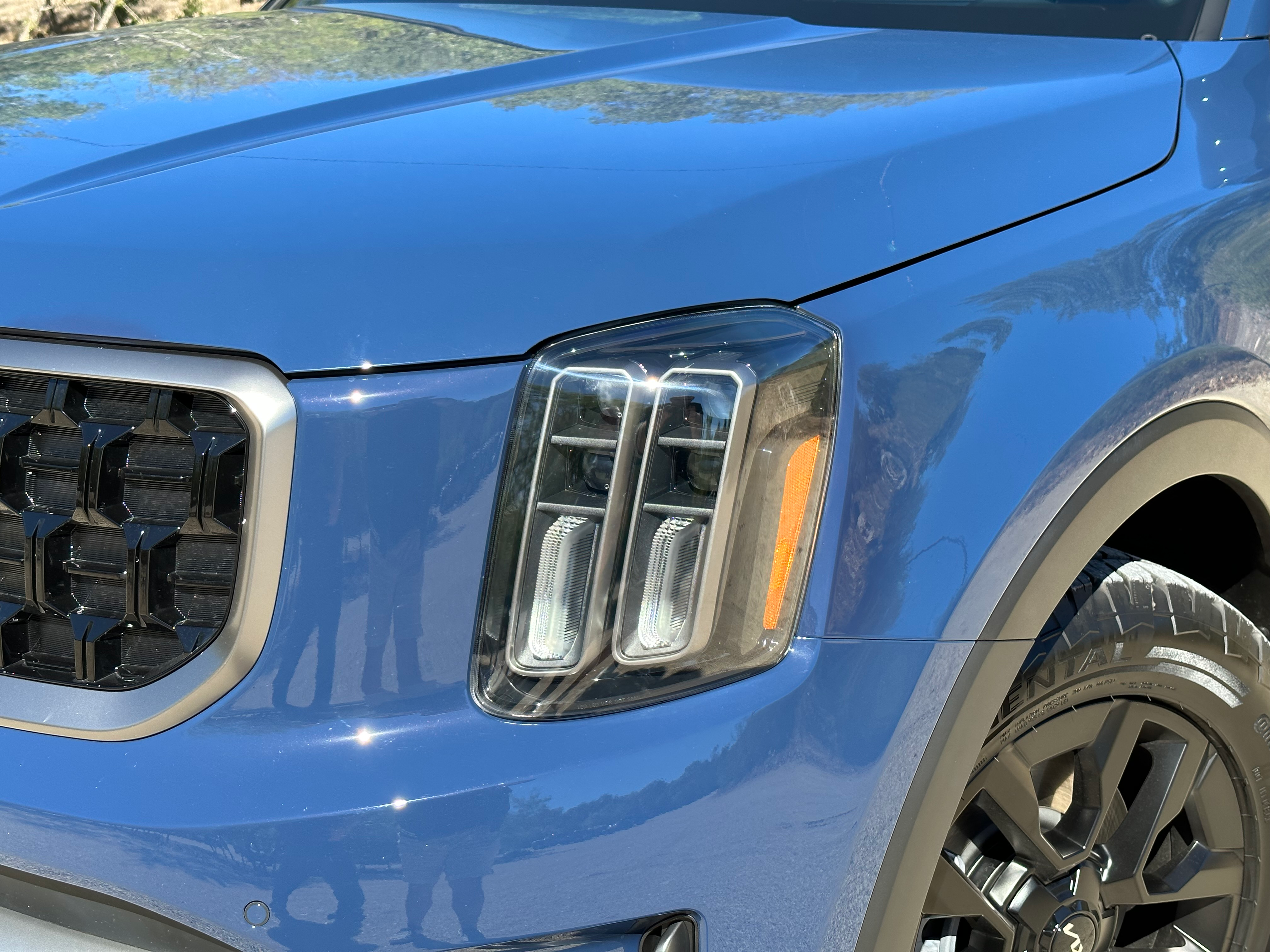 Close-up photo of the driver's side headlight on a 2023 Kia Telluride SX X-Pro painted blue.