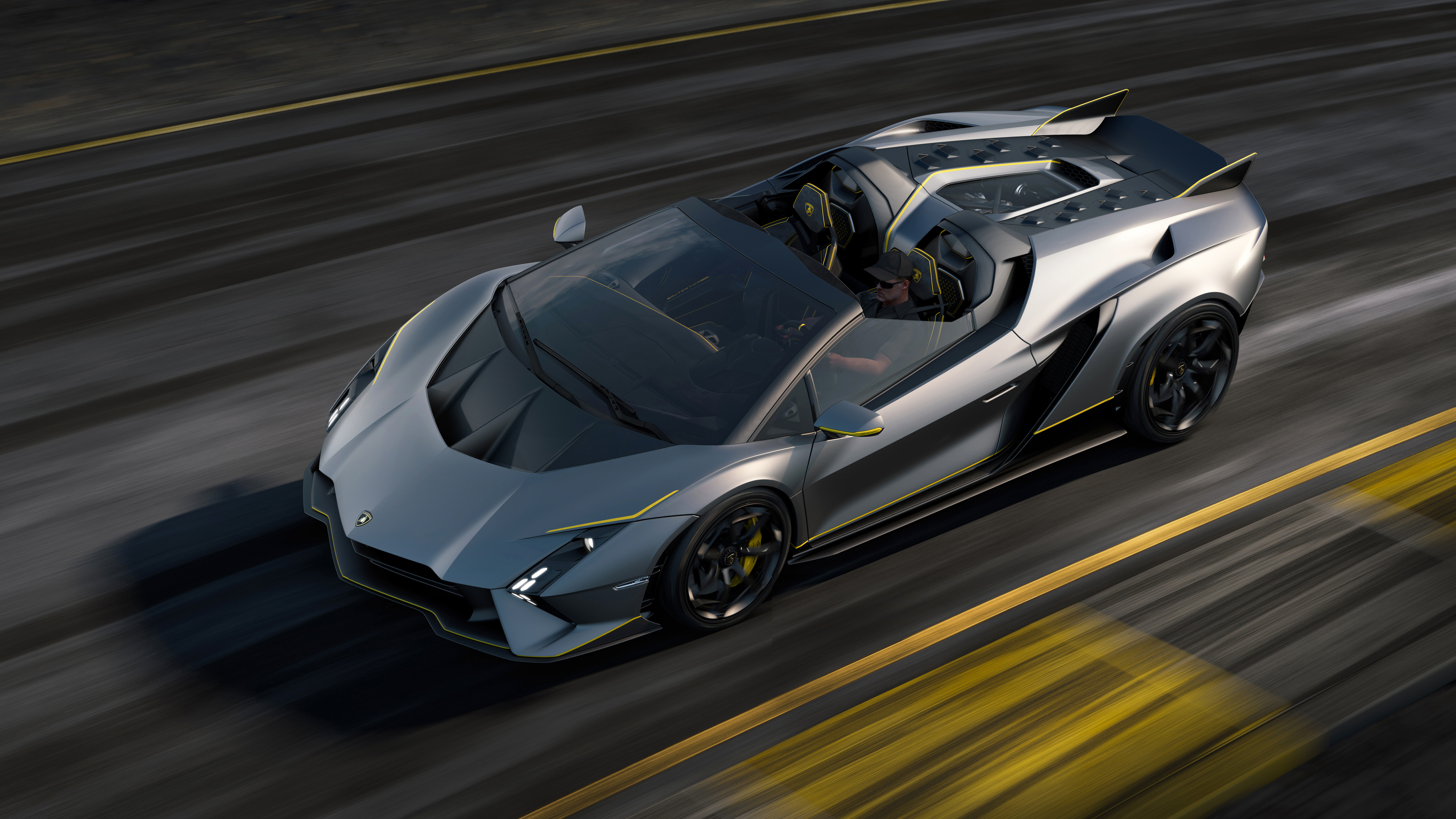 The gray Lamborghini Autentica roadster drives on-track, with the background image blurred with speed.