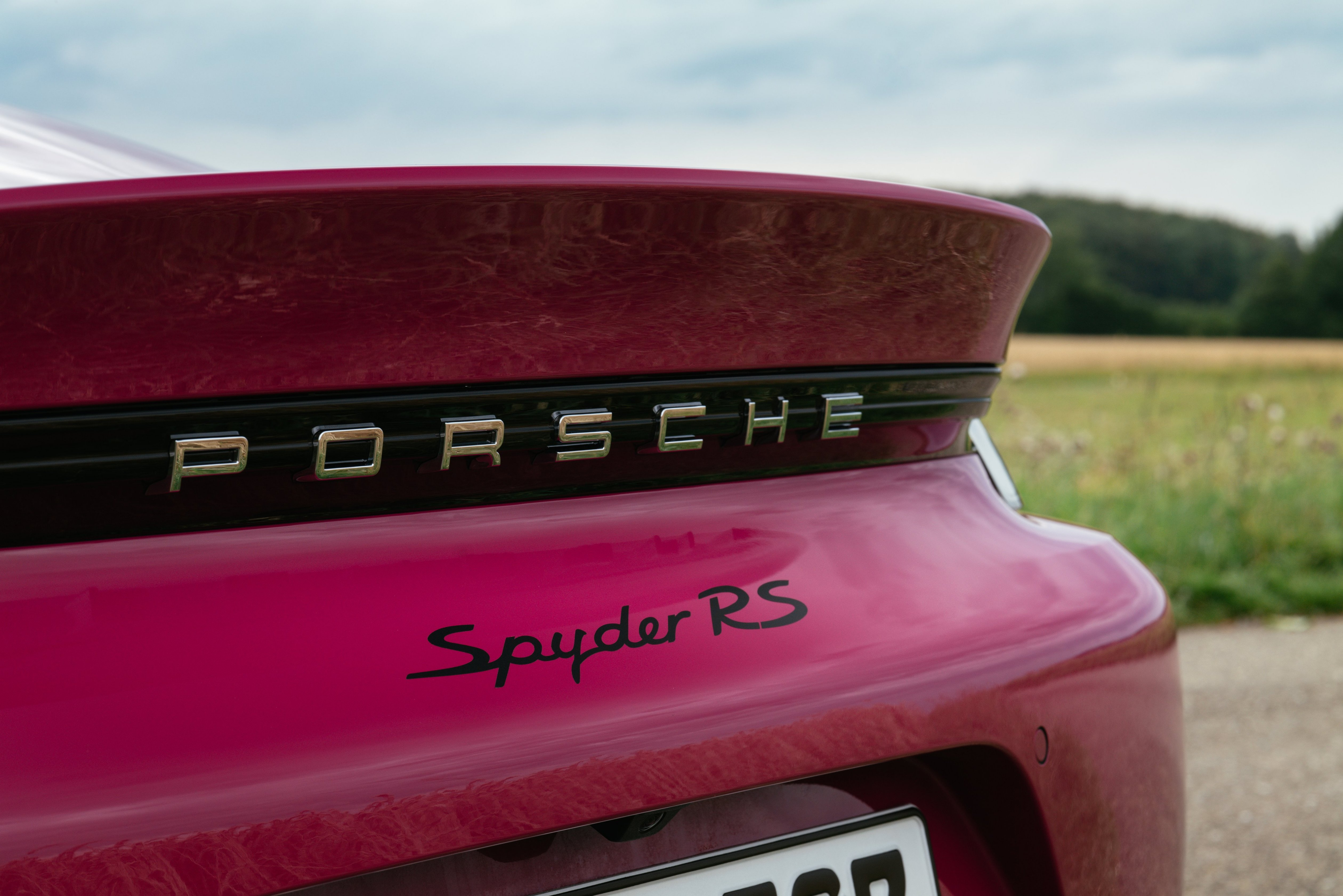 The rear spoiler of a 2023 Porsche 718 Spyder RS in Rubystone Neo