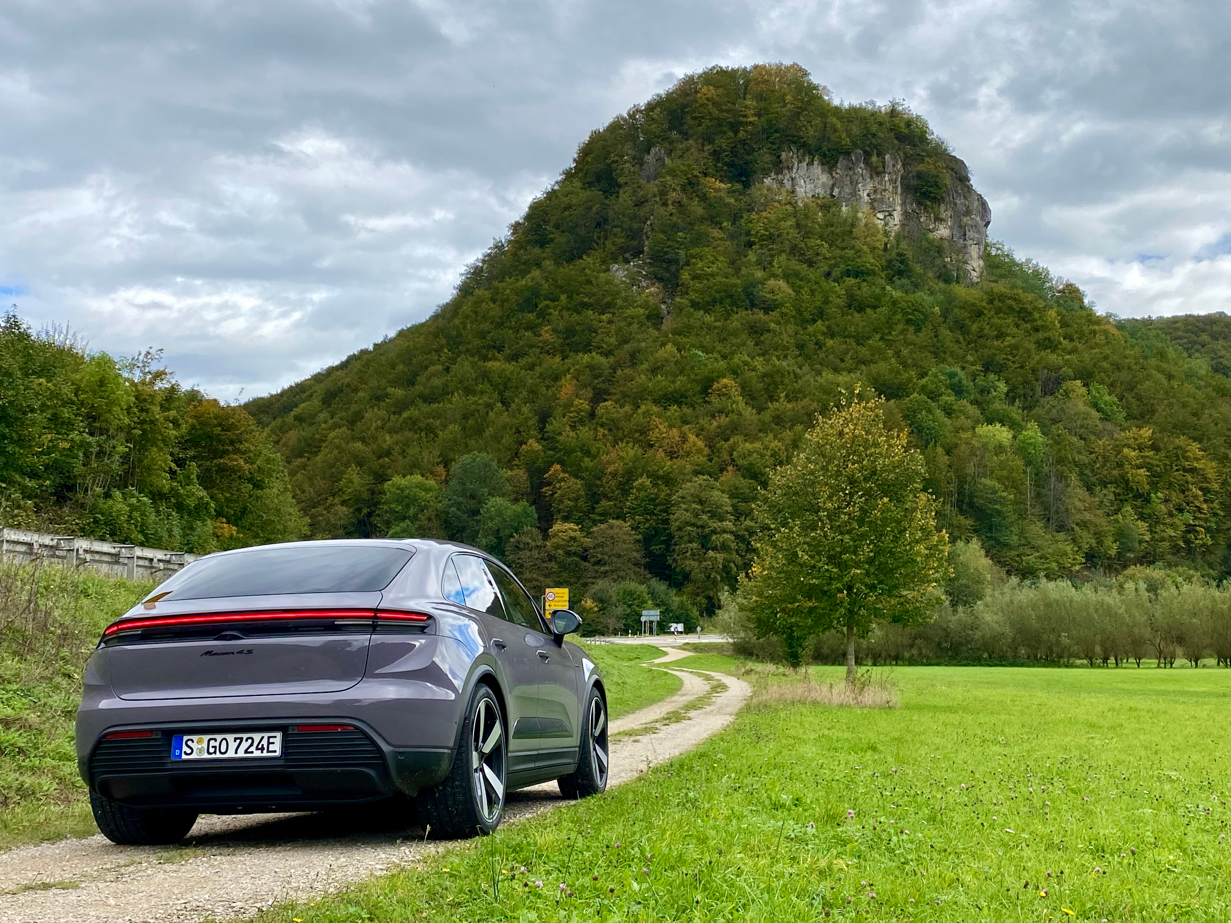 a rear 3/4 angle of the provence colroed Macan 4S in front of a big rock formation