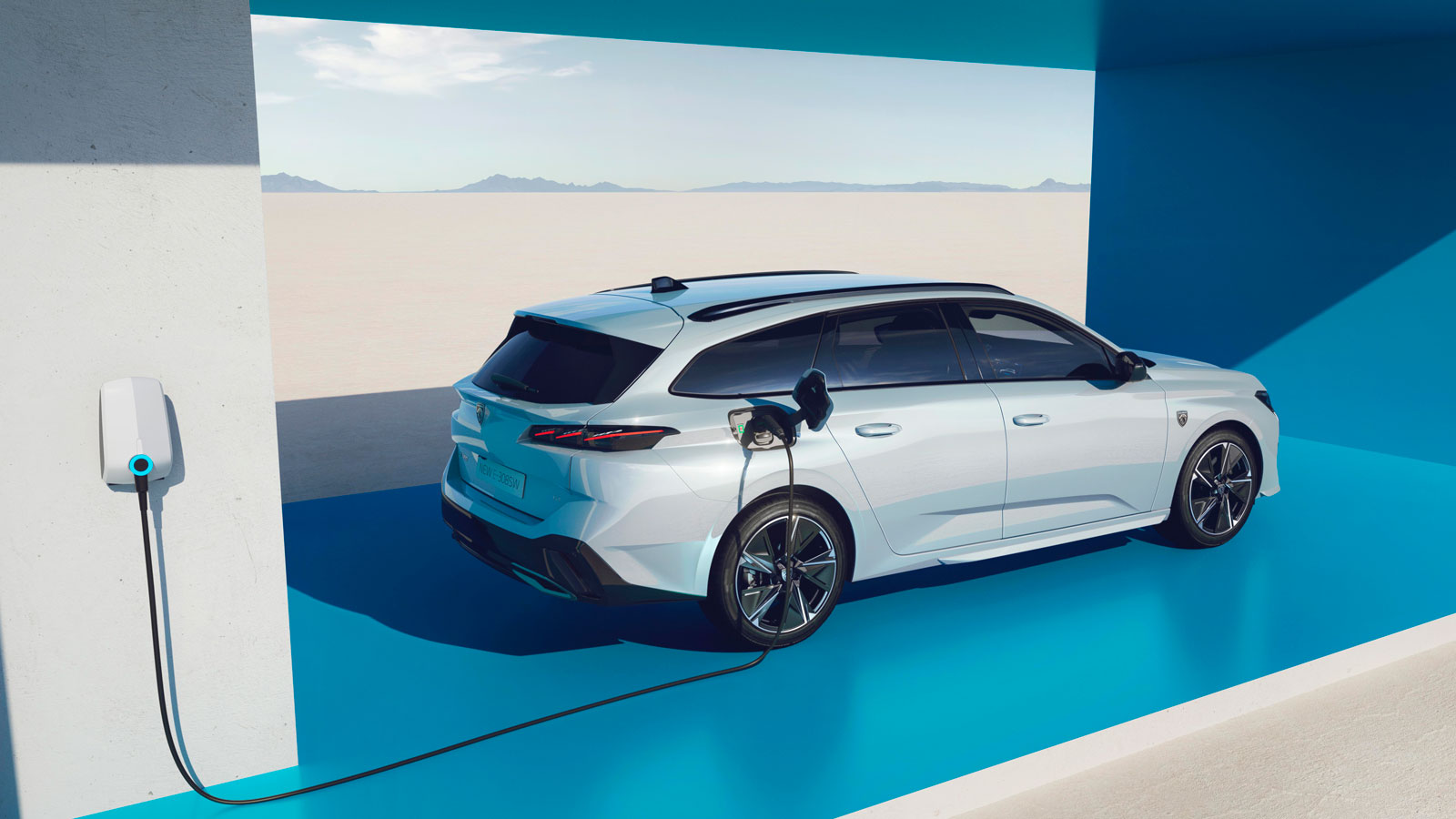 A photo of a white Peugeot 308 station wagon plugged in to charge. 