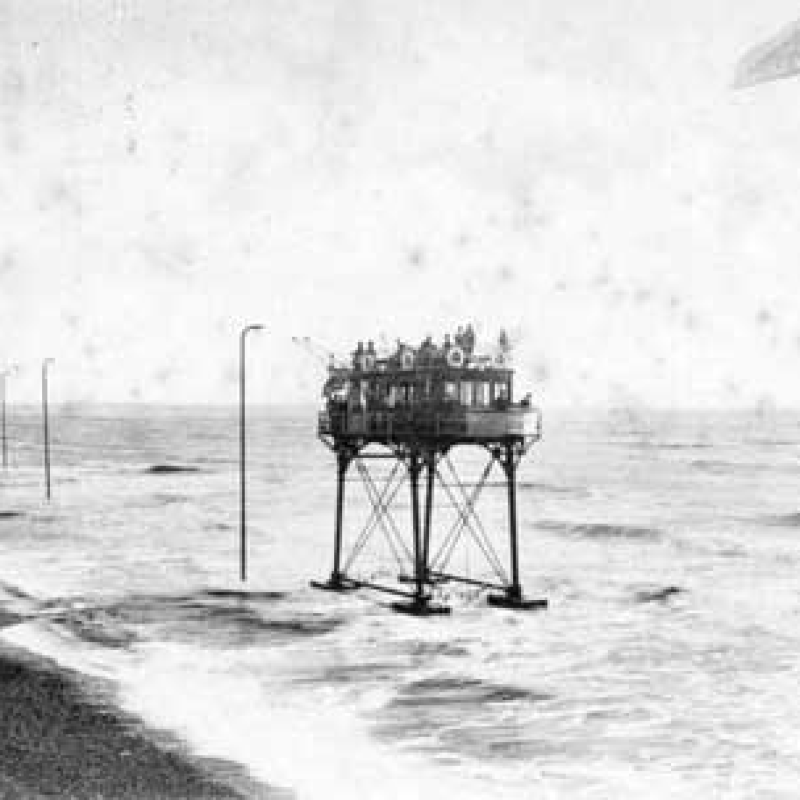 A black and white photo of an elevated train in Brighton. 