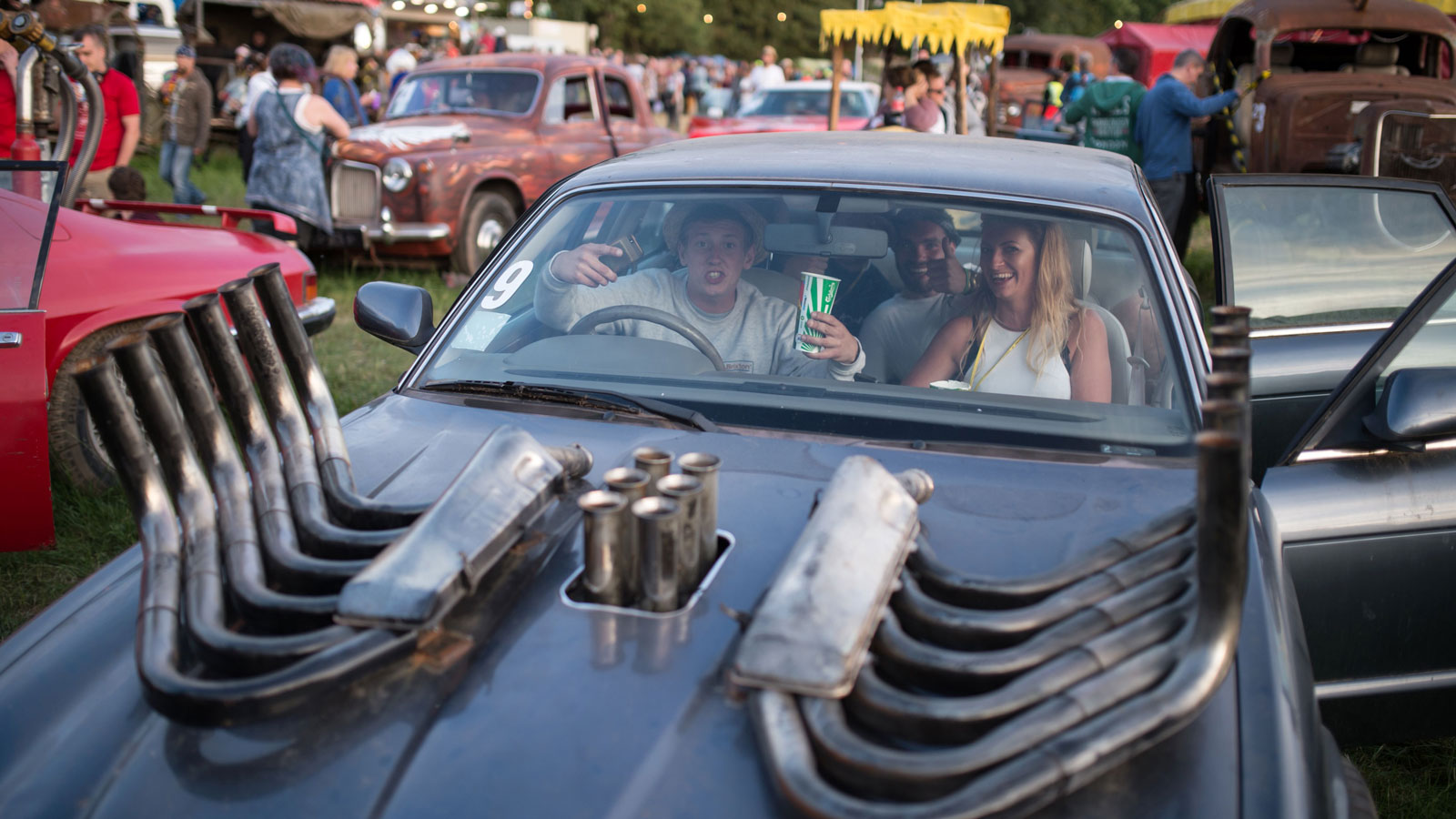 A photo of a group of people sat in a modified car at the Cineramageddon installation at Glastonbury. 