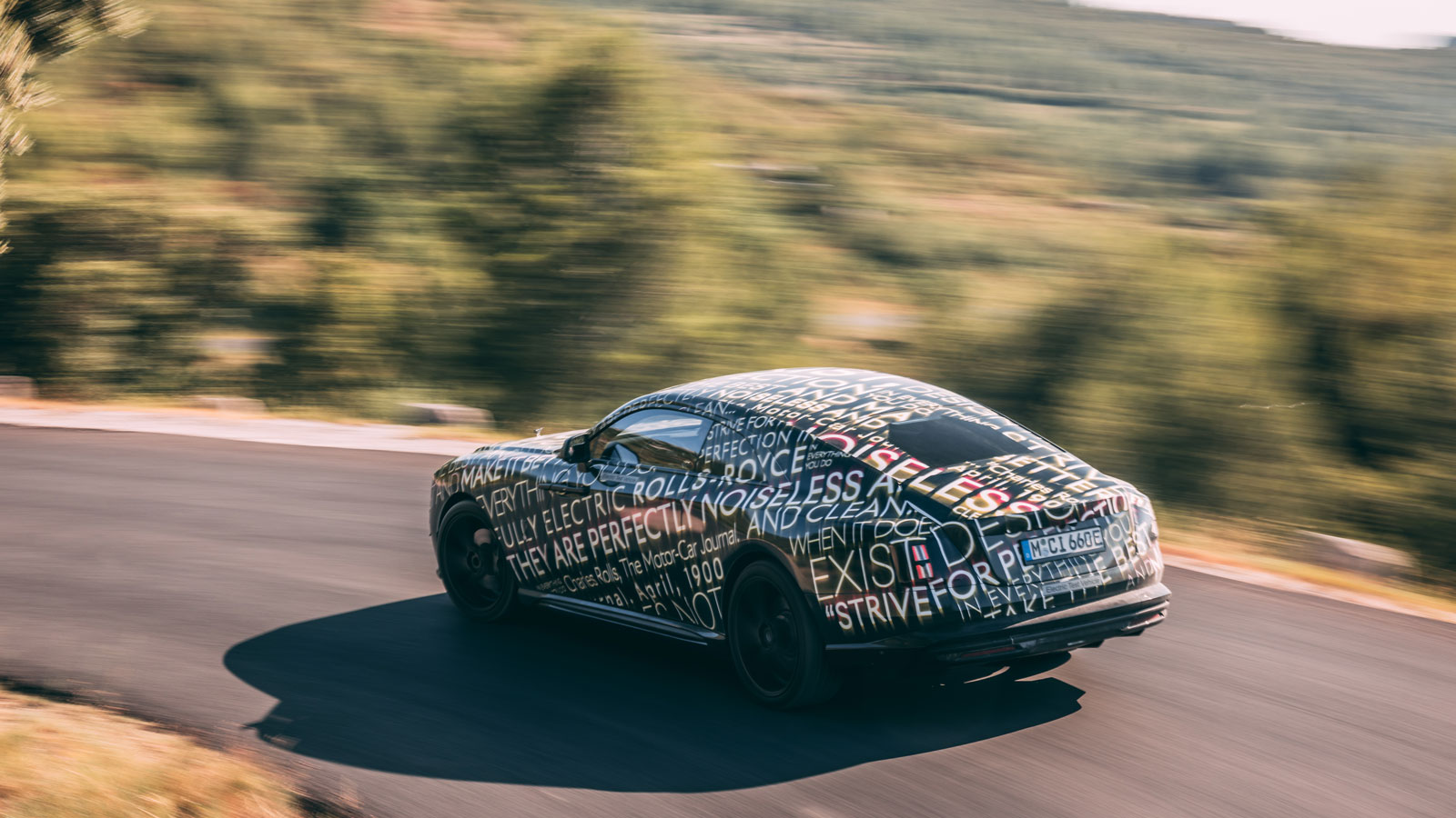 A photo of the rear of a camouflage Rolls Royce Spectre EV. 