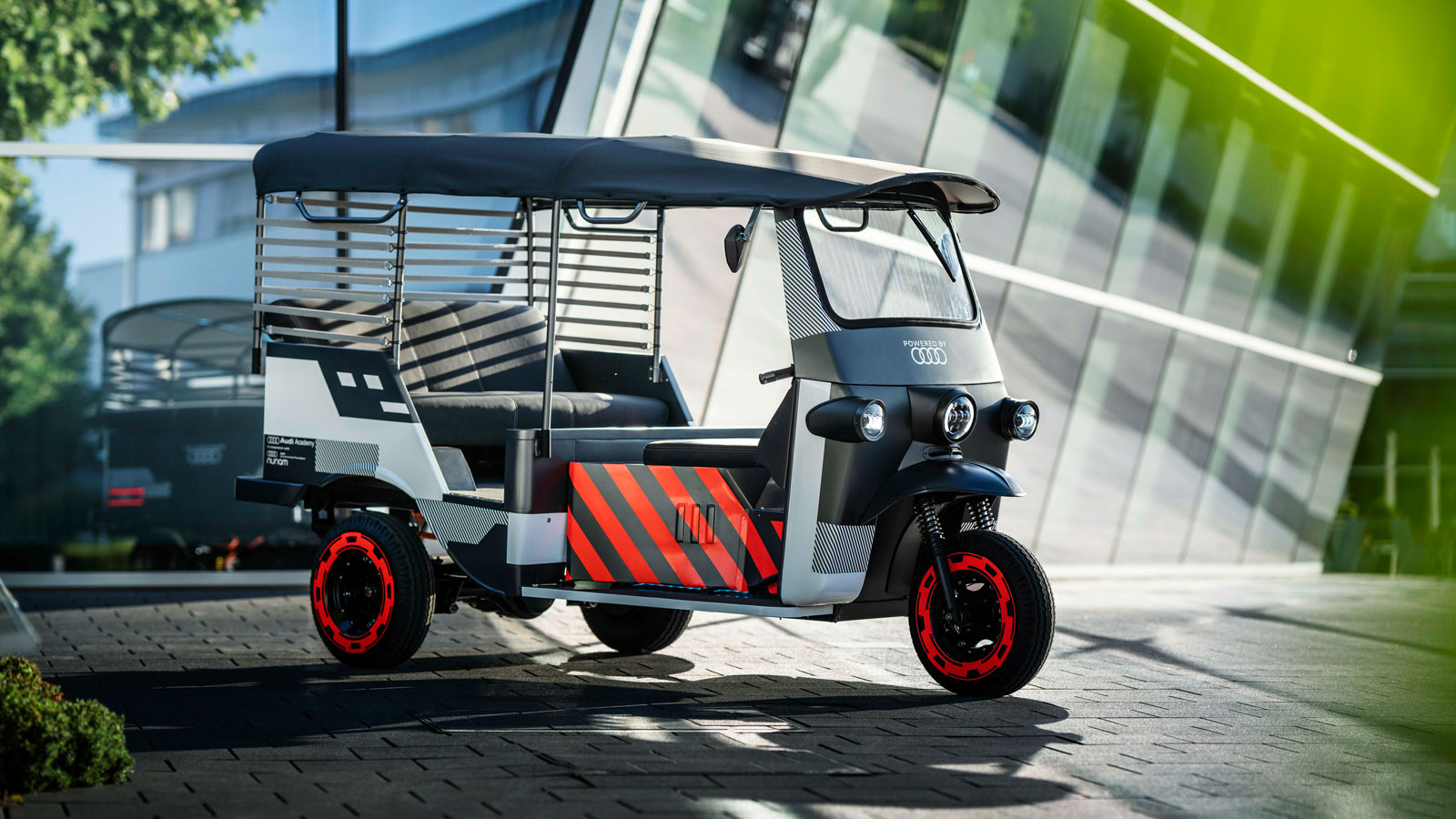 A photo of the Audi-branded rickshaw, which is painted gray with red details. 