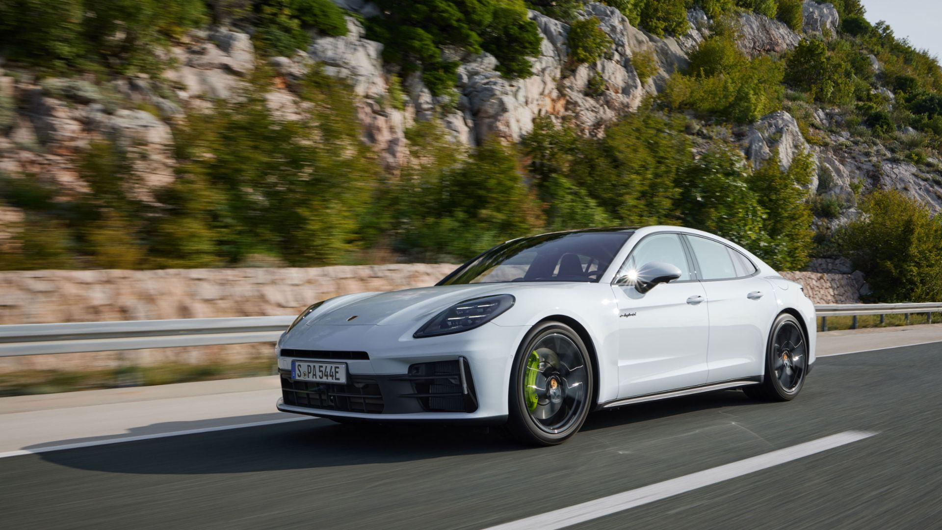 A white Porsche Panamera 4S E-Hybrid driving in front of a mountain 