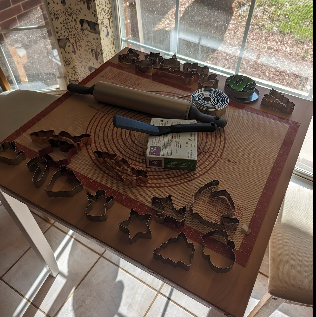 A table set up for crafting that includes race car-shaped cookie cutters, clay, and a silicon mat