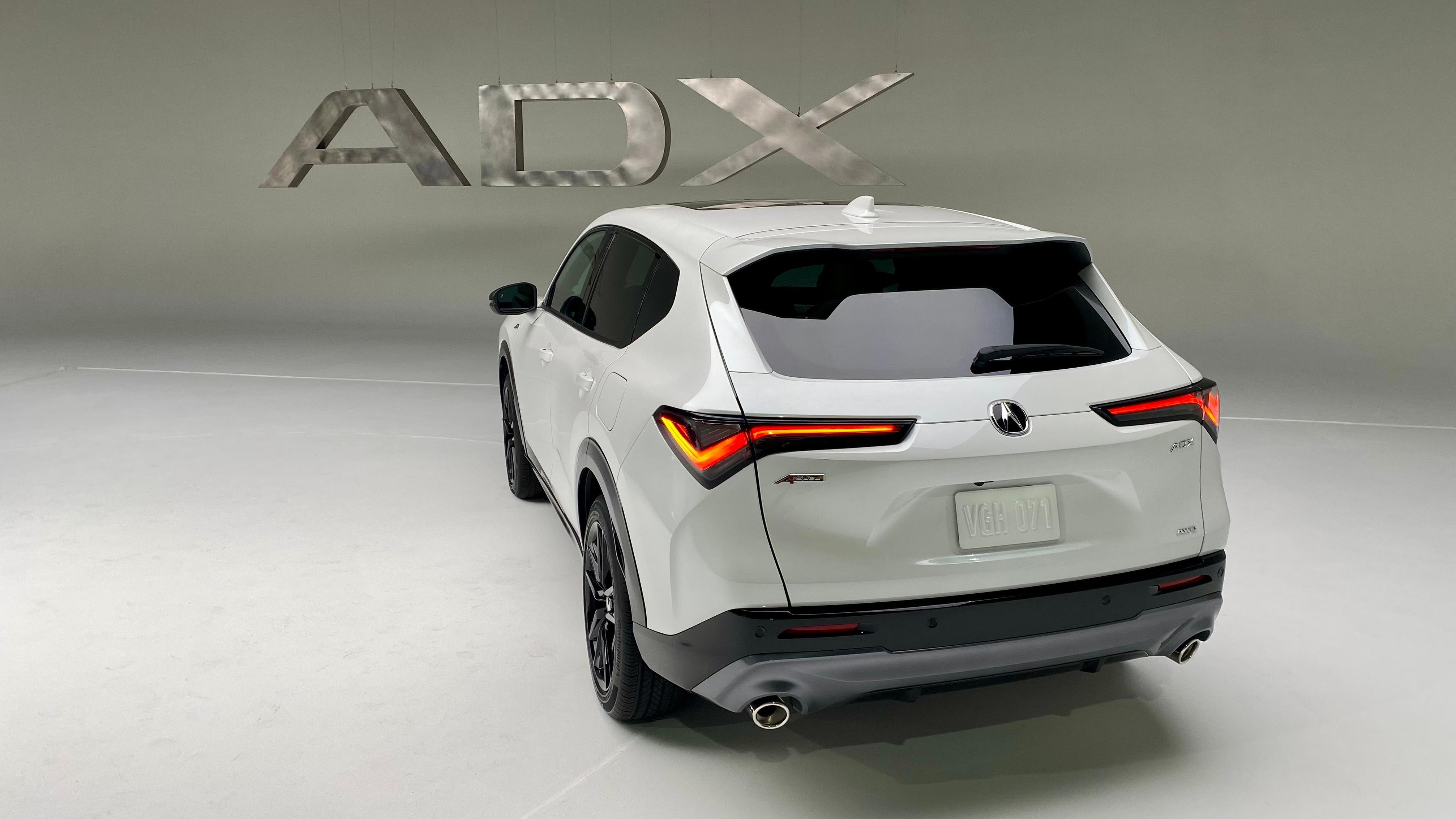 A photo of the rear of the white ADX in a white photo studio in front of a metal ADX sign