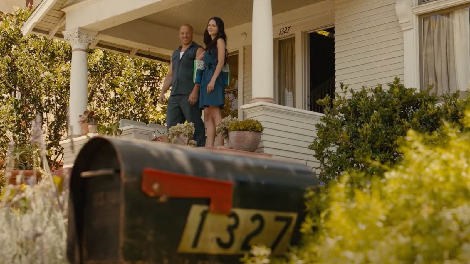 A screenshot from the Fast and Furious film showing two characters stood outside a house. 