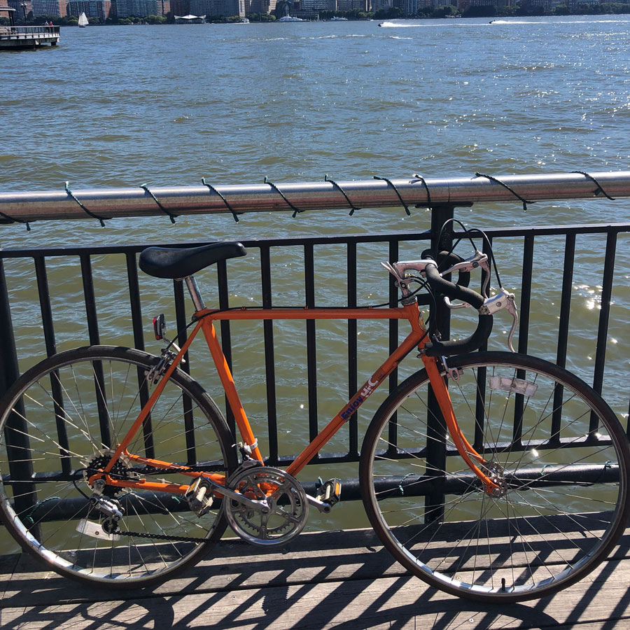 A photo of a bright orange bike leaning against a railing. 