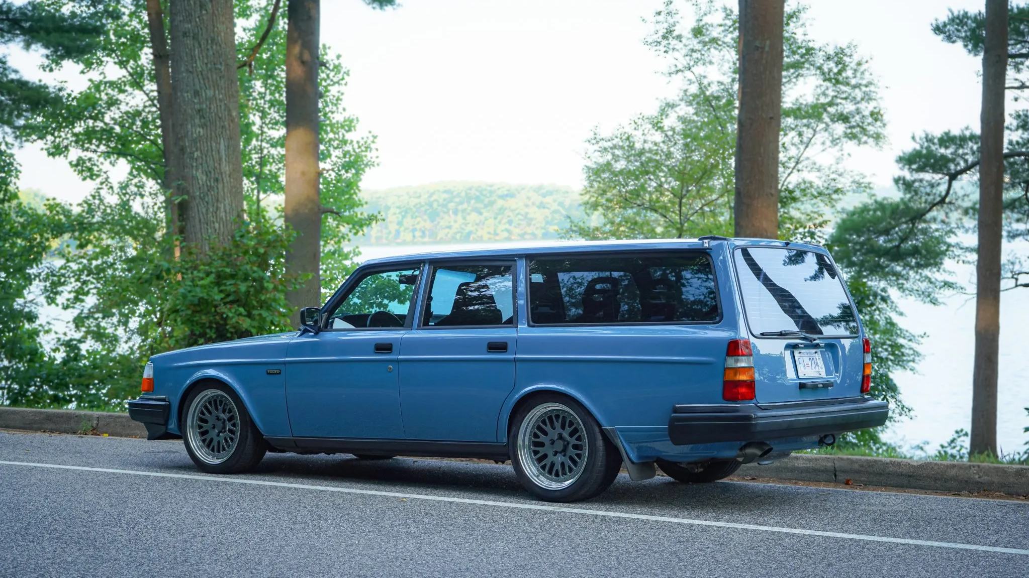 a rear 3/4 shot of the volvo wagon in front of trees