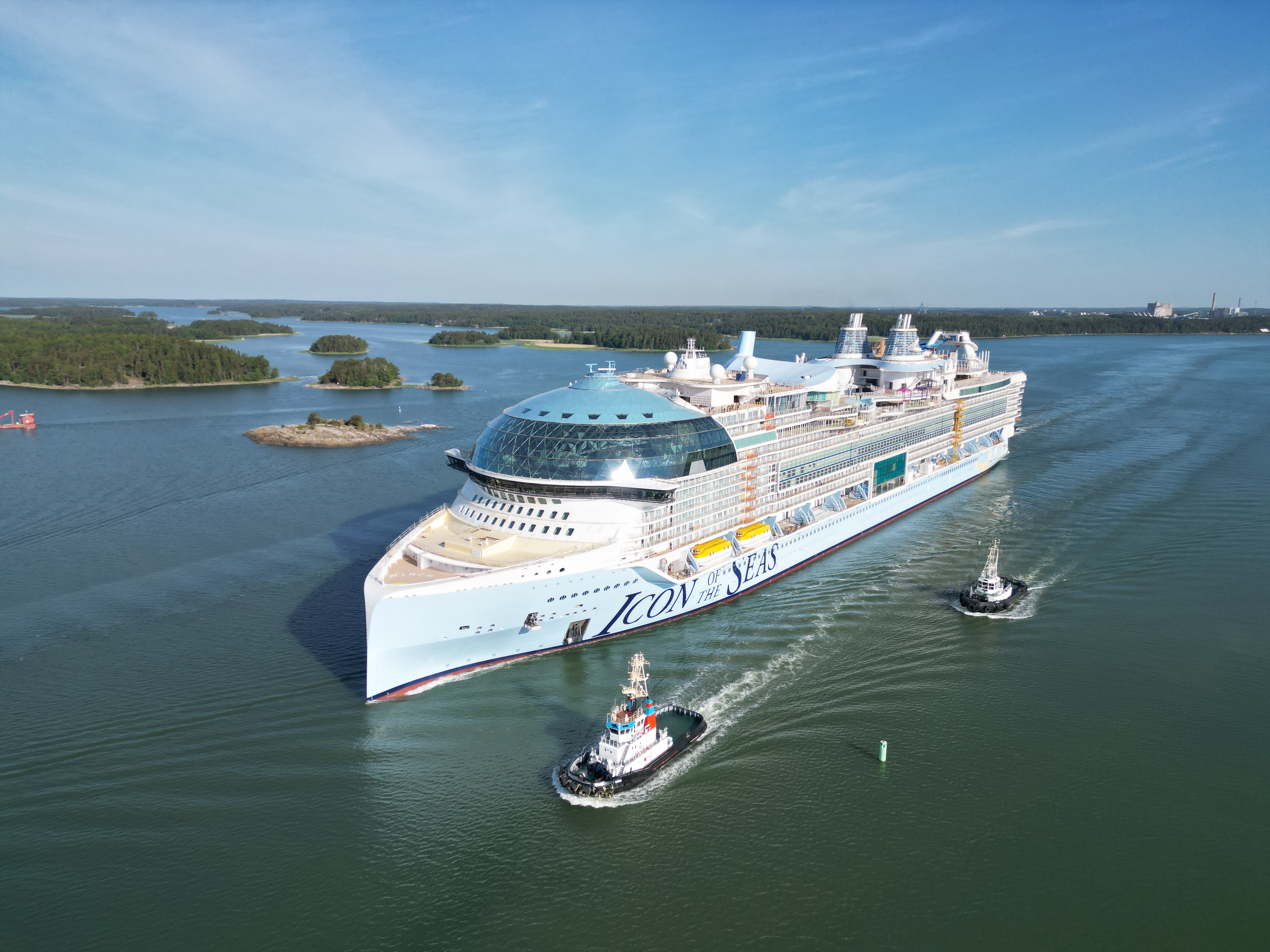 Icon of the Seas being escorted by tug boats