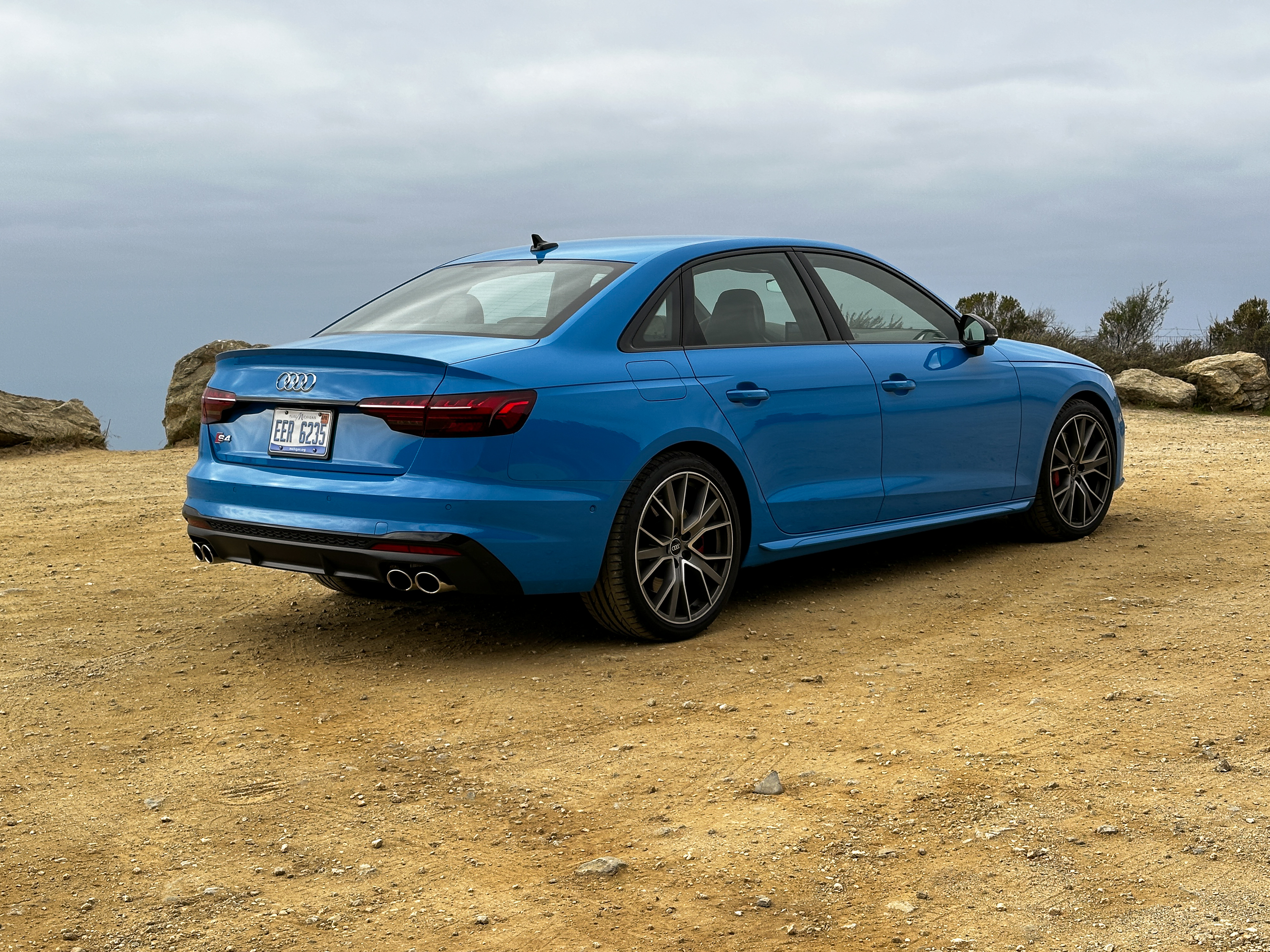 A 2022 Audi S4 is parked on dirt near a cliff, rear three-quarter view.