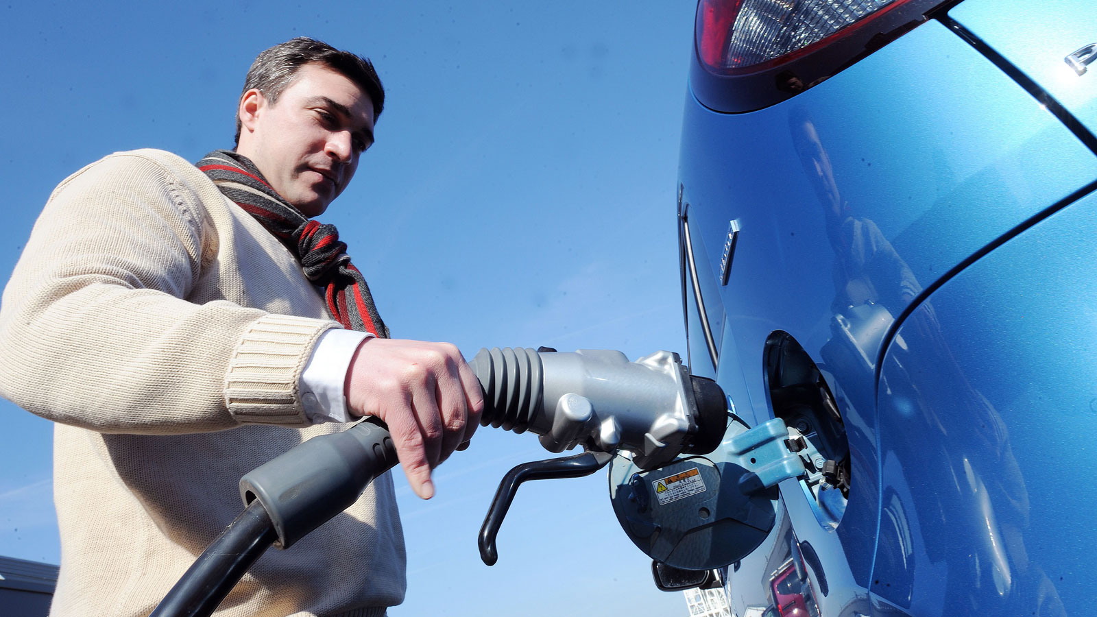 A man plugs his electric car into a charging cable. 